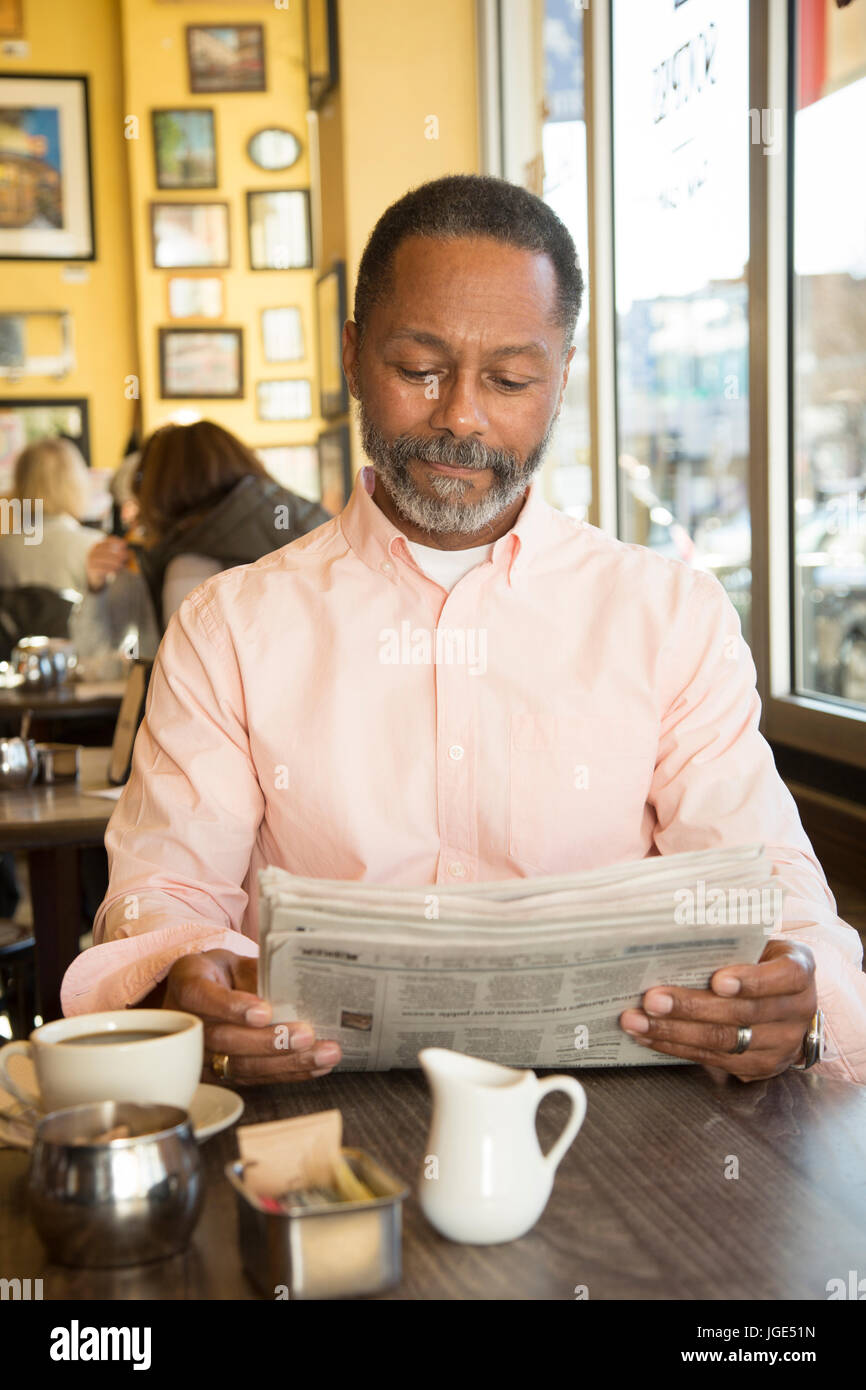Gemischte Rennen Mann liest Zeitung im Coffee-shop Stockfoto