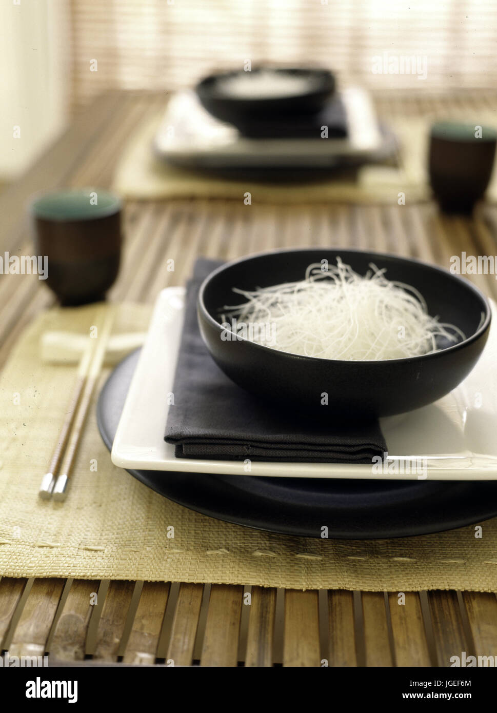 Orientalisches Essen in schwarz Schüsseln auf den Tisch mit den Stäbchen Stockfoto