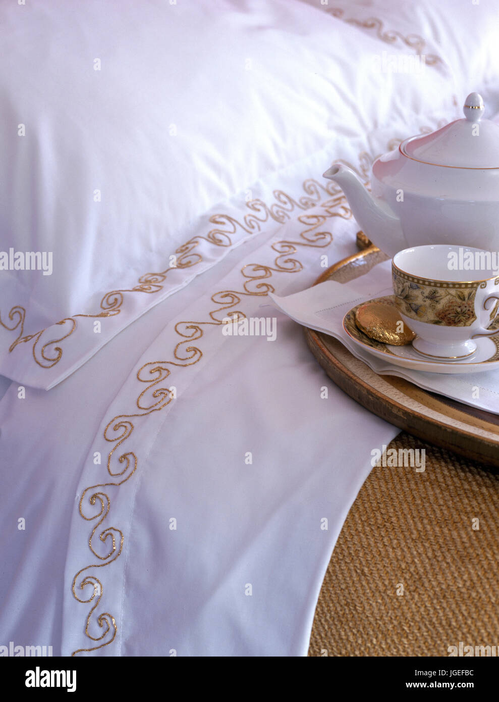 Weiße Bettwäsche mit Gold thread Stickerei und Fach mit Teekanne und Schale Stockfoto