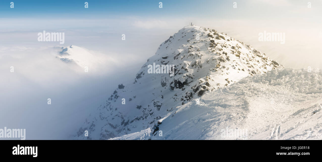 Chopok Gipfel auf verschneiten Winterzeit mit Sonnenstrahlen Effekt über den Wolken. Stockfoto