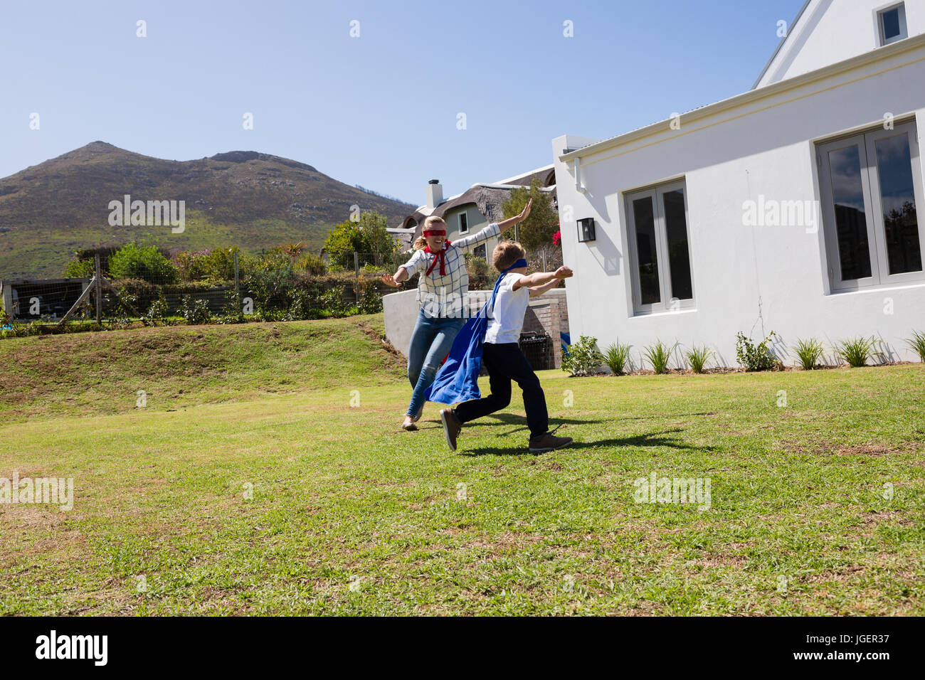 Mutter und Sohn in Superhelden-Kostüm an einem sonnigen Tag im Hinterhof spielen Stockfoto