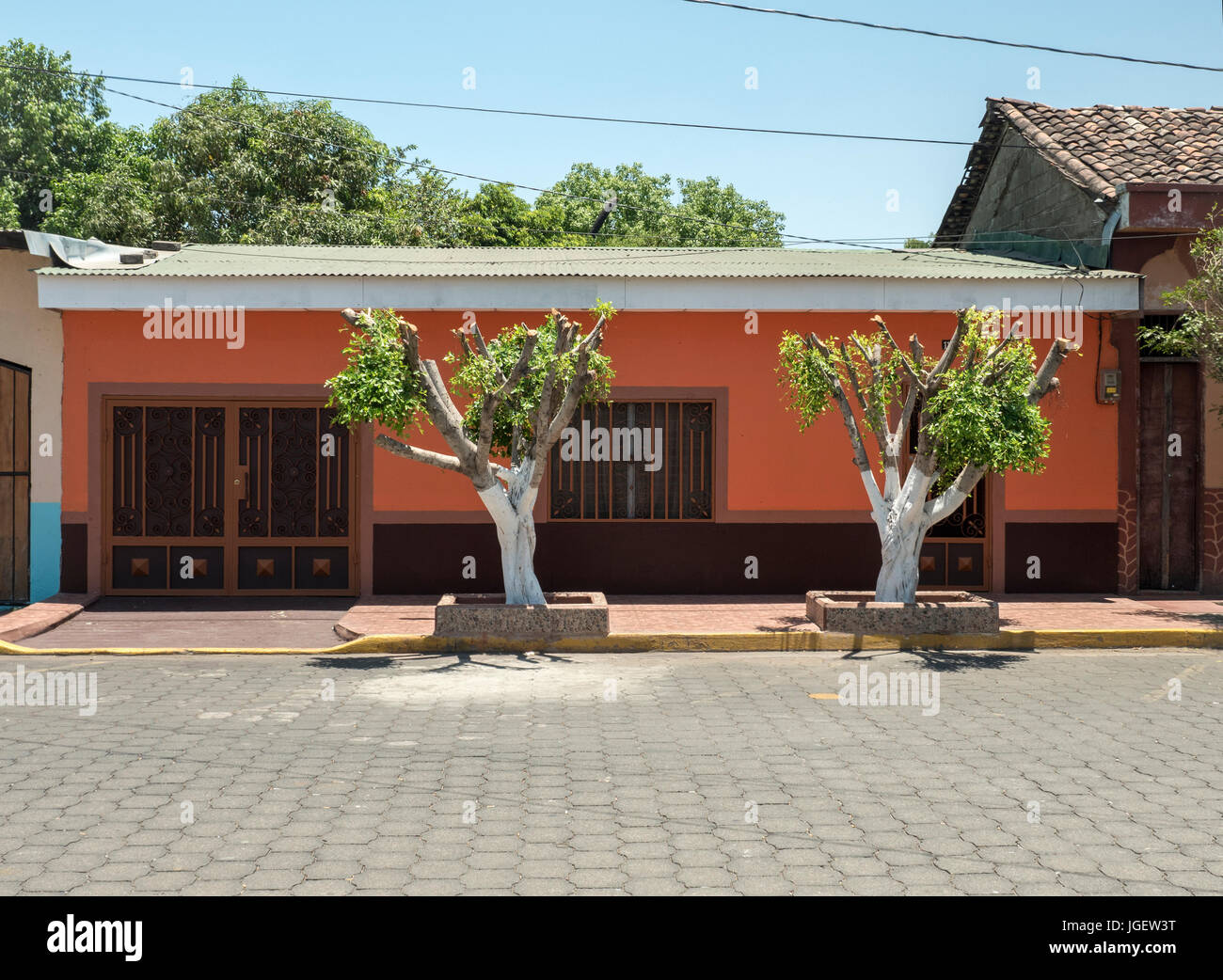 Ein rot lackiert altes Haus mit zwei Bäumen auf der Straße In der Innenstadt von Corinto Nicaragua Stockfoto