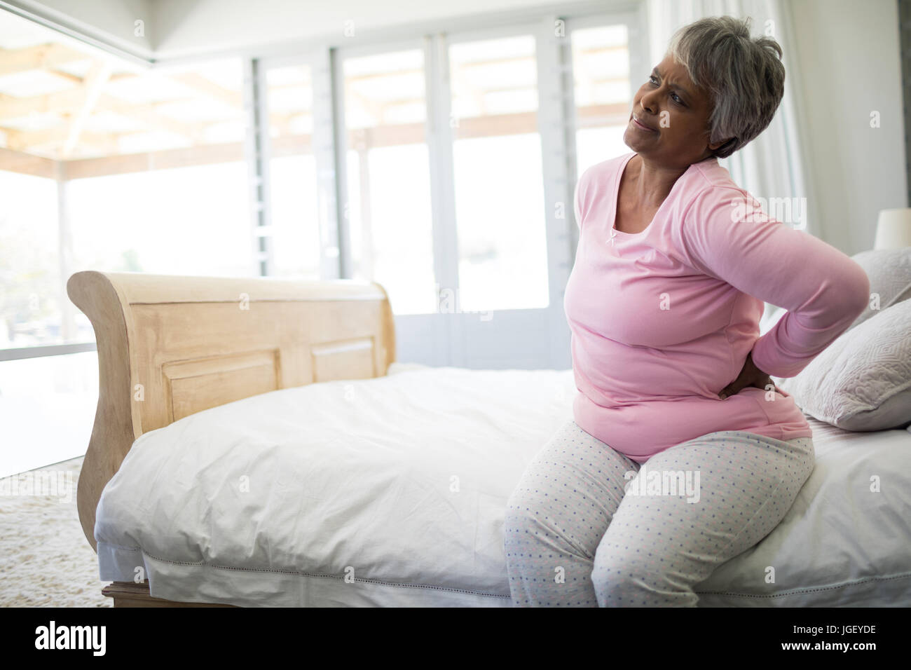 Ältere Frau, die Schmerzen im Rücken im Schlafzimmer zu Hause Stockfoto