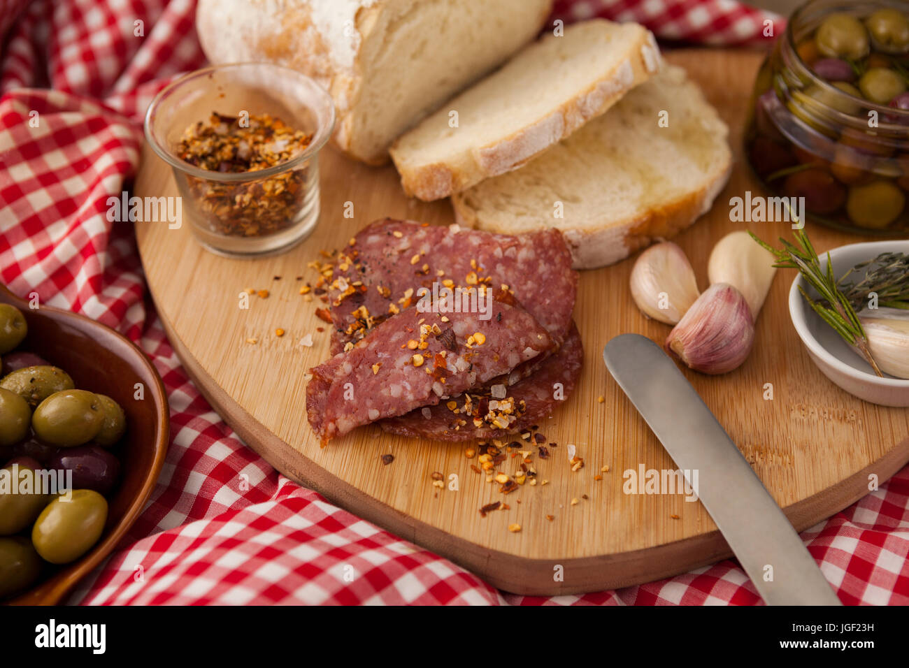 Chili-Flocken auf Fleisch vom Brot mit Oliven im Glas am Tisch Stockfoto
