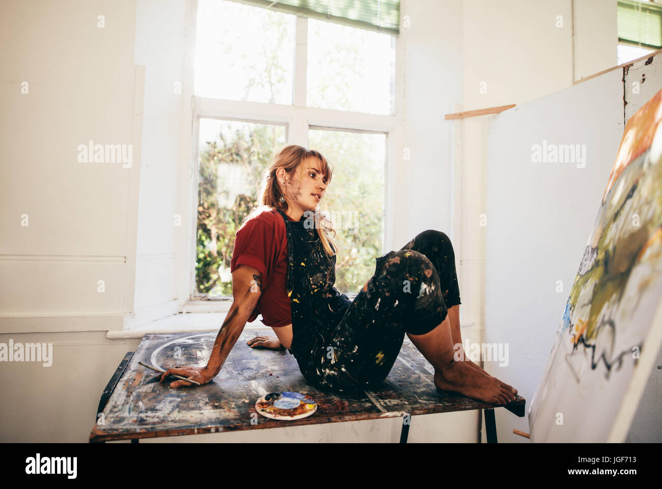 Innenaufnahme der Malerin in Studio zu arbeiten. Junge Frau entspannt Künstler Malerei in ihrem Atelier und denken zu betrachten. Stockfoto