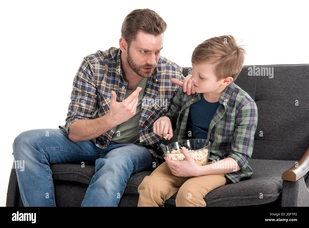 Vater mit Sohn auf dem Sofa sitzen und Essen Popcorn aus Schüssel, Familienprobleme Konzept sprechen Stockfoto