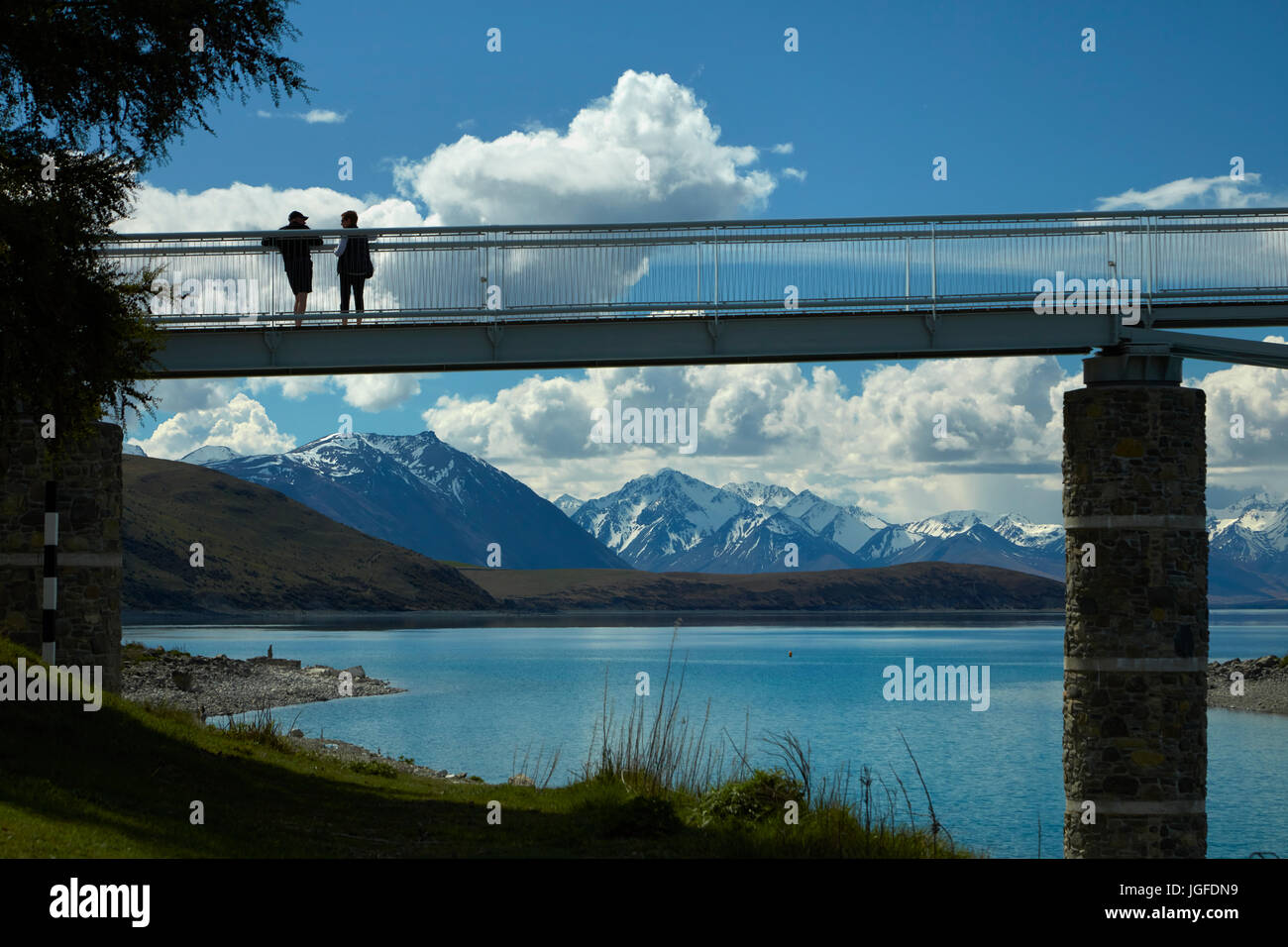 Touristen auf Fußgängerbrücke über Lake Tekapo Steckdose zur Kirche des guten Hirten, Mackenzie Country, Canterbury, Südinsel, Neuseeland Stockfoto