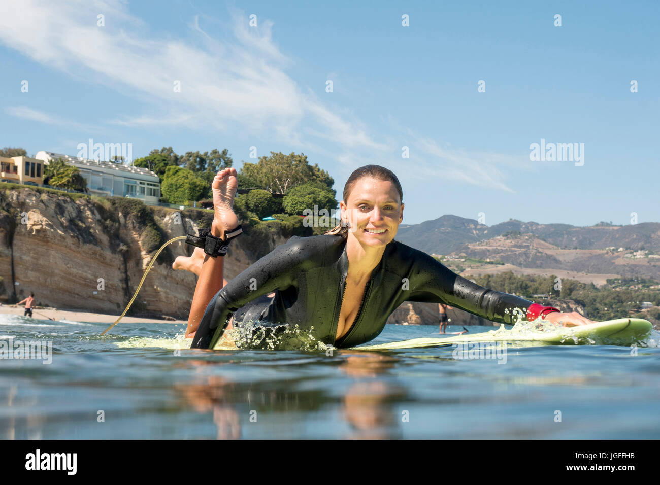 Lächelnde Frau kaukasischen Paddeln auf Surfbrett im Ozean Stockfoto