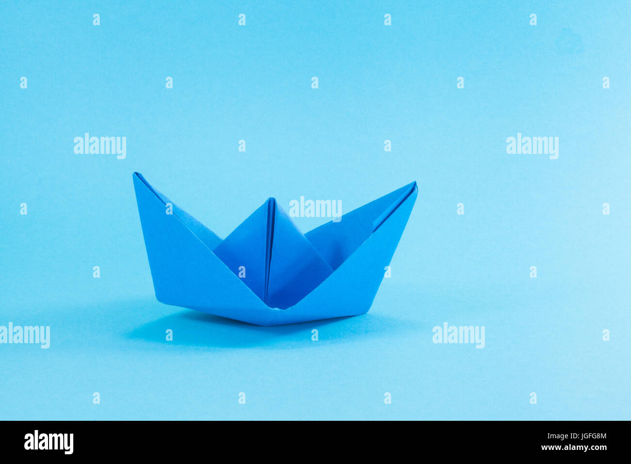 Papierschiff auf Cyan Hintergrund blau. Stockfoto