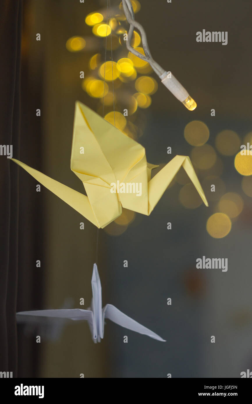 Papier-gelbem Kranich-Origami auf einem dunklen Hintergrund Weihnachtsgirlande. Stockfoto