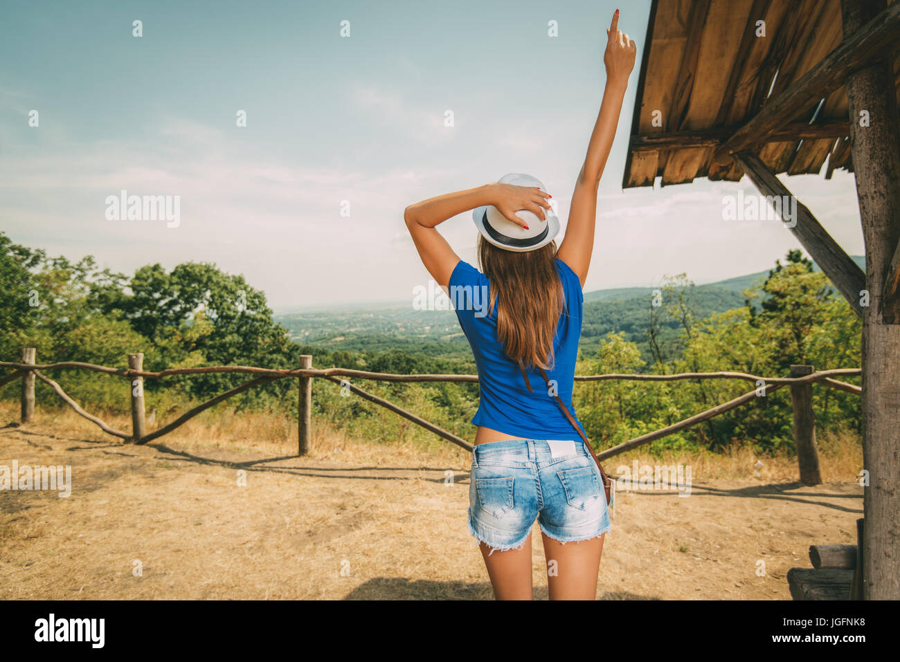 Stets gut gelaunte Frau im Sommer Reisen Urlaub stehen mit dem Aussichtspunkt mit ausgestrecktem Arm. Sicht nach hinten. Stockfoto