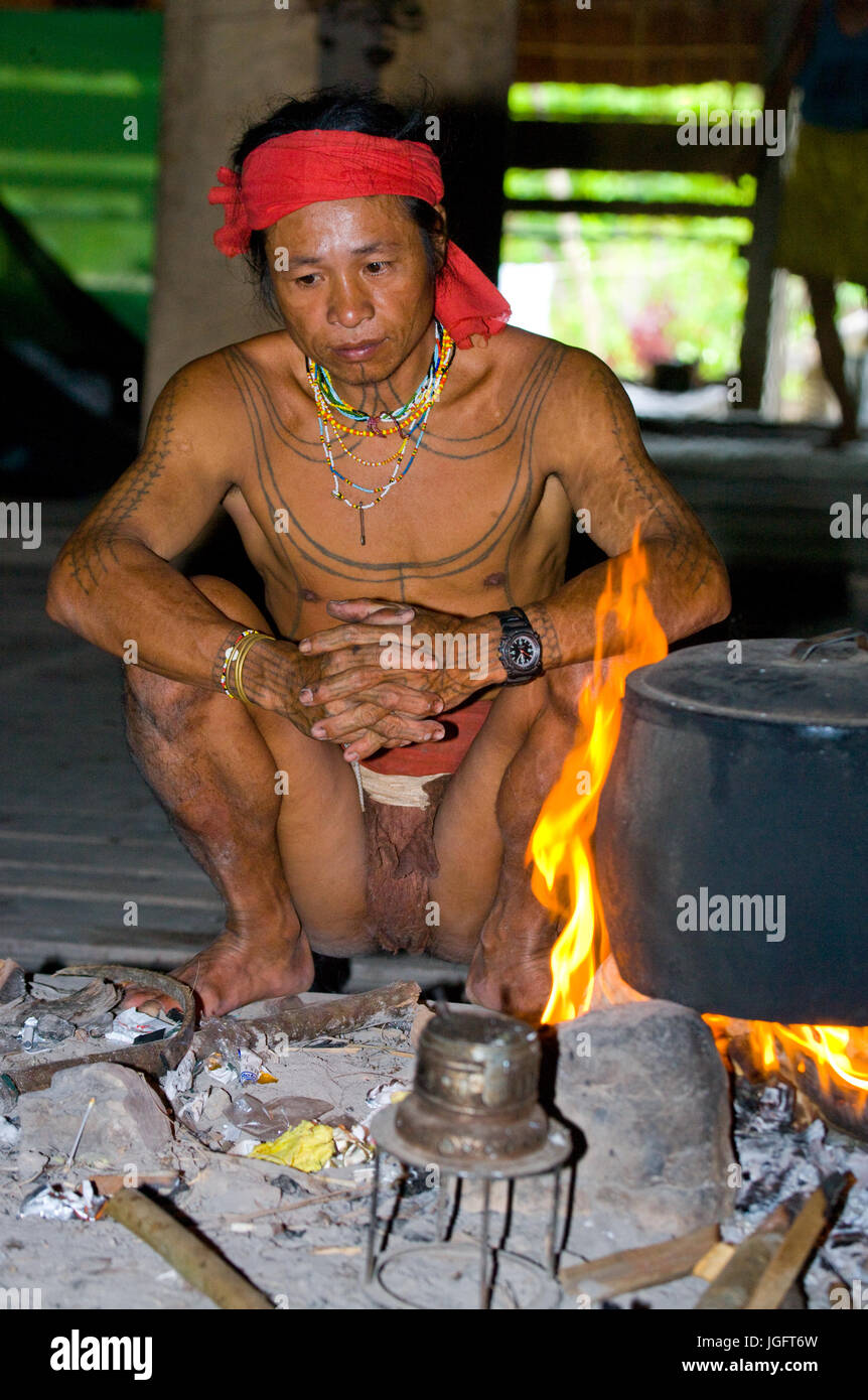 MENTAWAI Leute, WEST-SUMATRA Insel SIBERUT, Indonesien – 16. November 2010: Mann Mentawai Stamm sitzen am Feuer im Haus Stockfoto