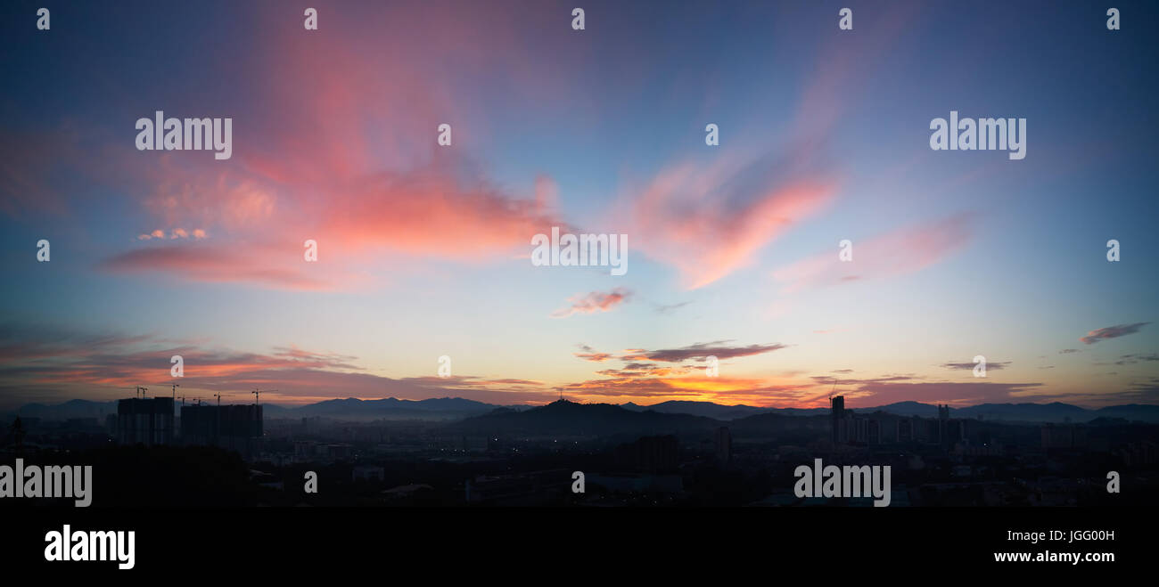 Wunderschönes Panorama natürliche Sonnenuntergang Sonnenaufgang über Silhouetten Skyline und erstaunliche orange Wolke blauer Himmel darüber. Stockfoto