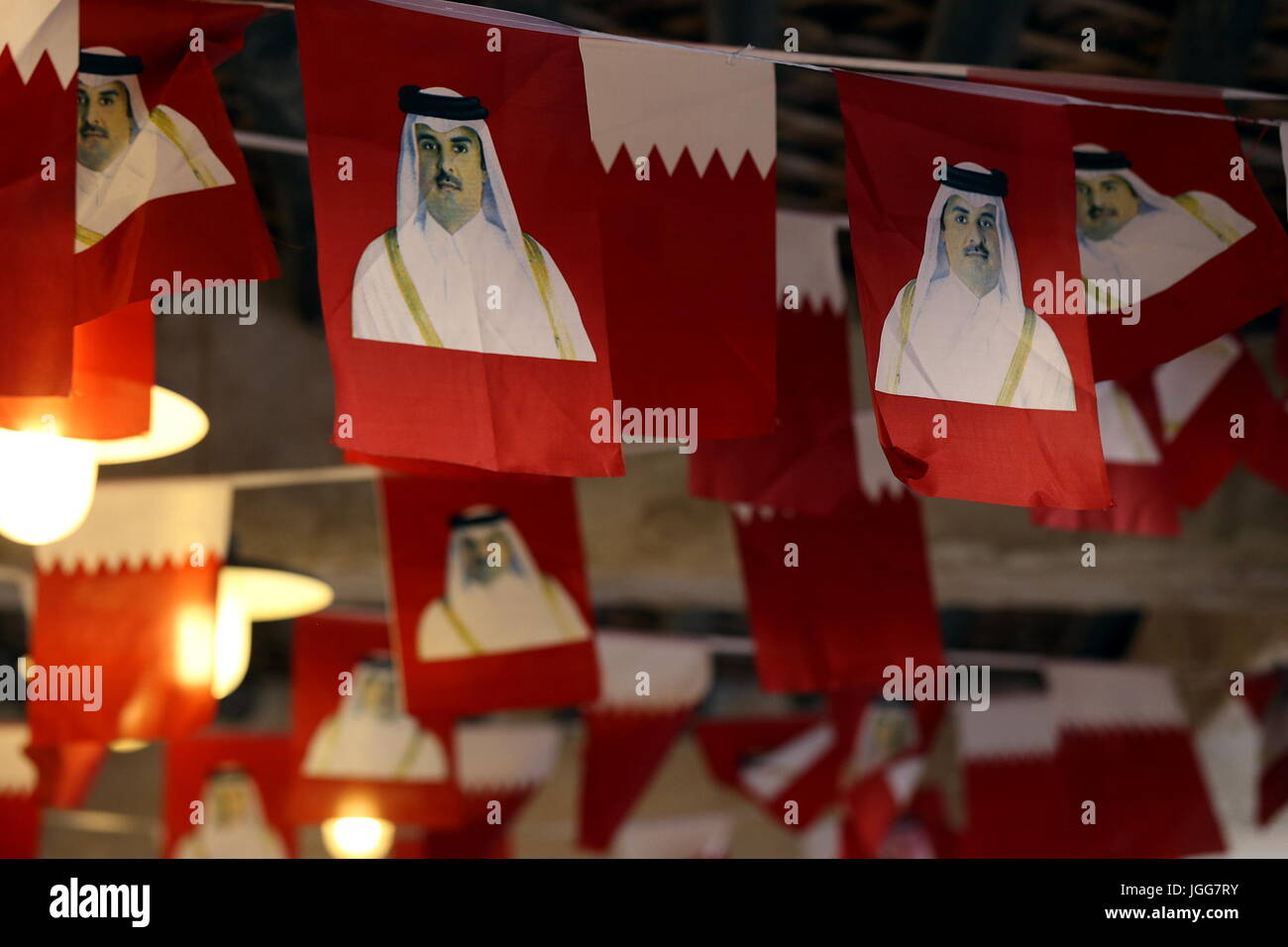 DOHA, Katar - 6. Juli 2017: Nationales Fahnen gedruckt mit Bildern der Qatari Emir Scheich Tamim bin Hamad al-Thani über die Decke aufgereiht sind im Souq Waqif-Markt während der diplomatischen Krise zwischen Katar und arabischen Nachbarstaaten Stockfoto