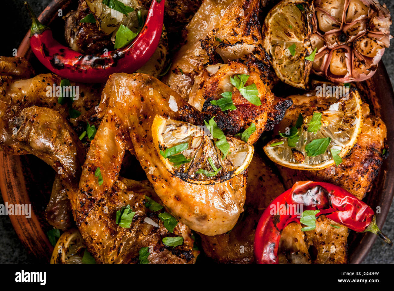 Sommer essen. Ideen für Grill, Grill-Party. Hähnchenschenkel, Flügel, gegrillt, gebraten in Brand. Mit hot Chili-Pfeffer Zitrone und Bbq-sauce. Dunkle Steintisch Stockfoto