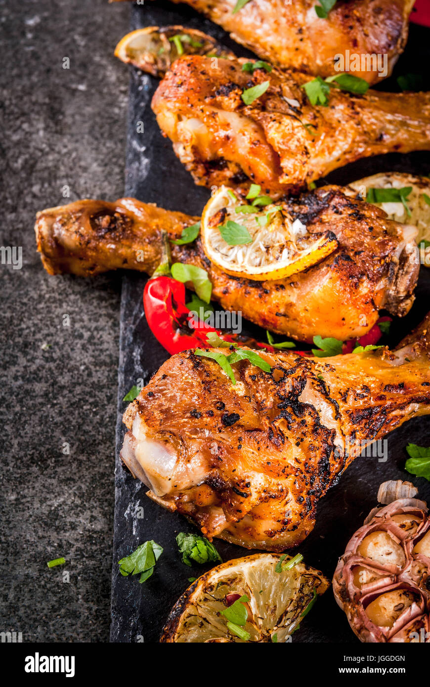 Sommer essen. Ideen für Grill, Grill-Party. Hähnchenschenkel, Flügel, gegrillt, gebraten in Brand. Mit hot Chili-Pfeffer Zitrone und Bbq-sauce. Dunkle Steintisch Stockfoto