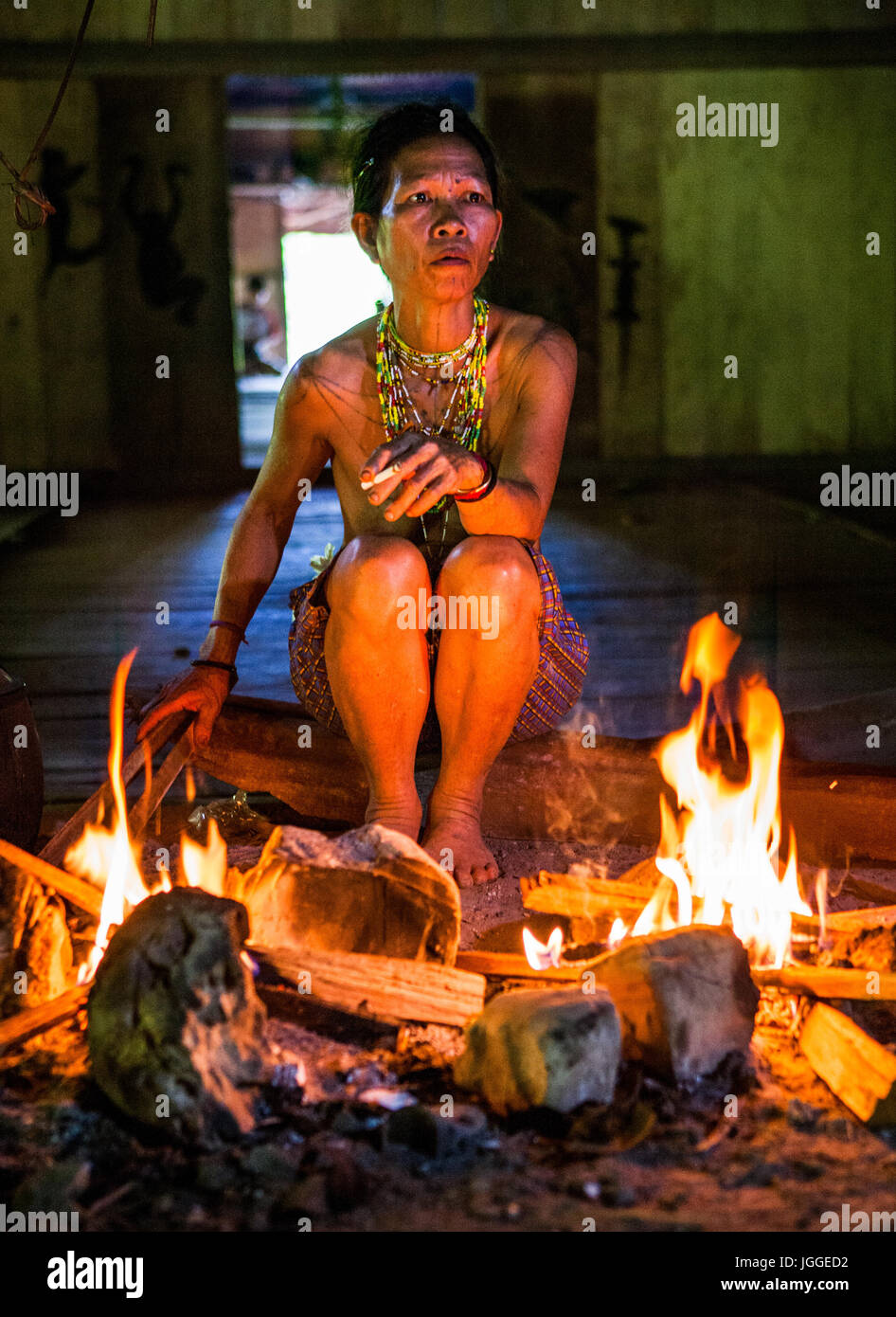 MENTAWAI Leute, WEST-SUMATRA Insel SIBERUT, Indonesien-03 OKTOBER 2011: Frau Mentawai Stamm am Feuer in einem traditionellen Haus sitzen. Stockfoto