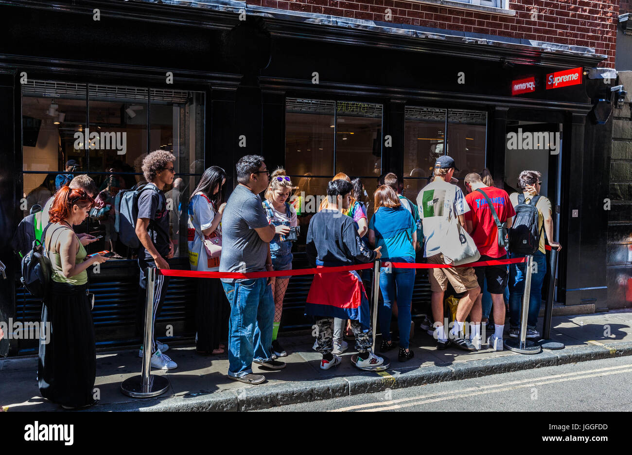Eine Schlange junger Leute, die vor dem trendigen Geschäft Supreme in der Peter Street, Soho, London, England, Großbritannien warten. Stockfoto
