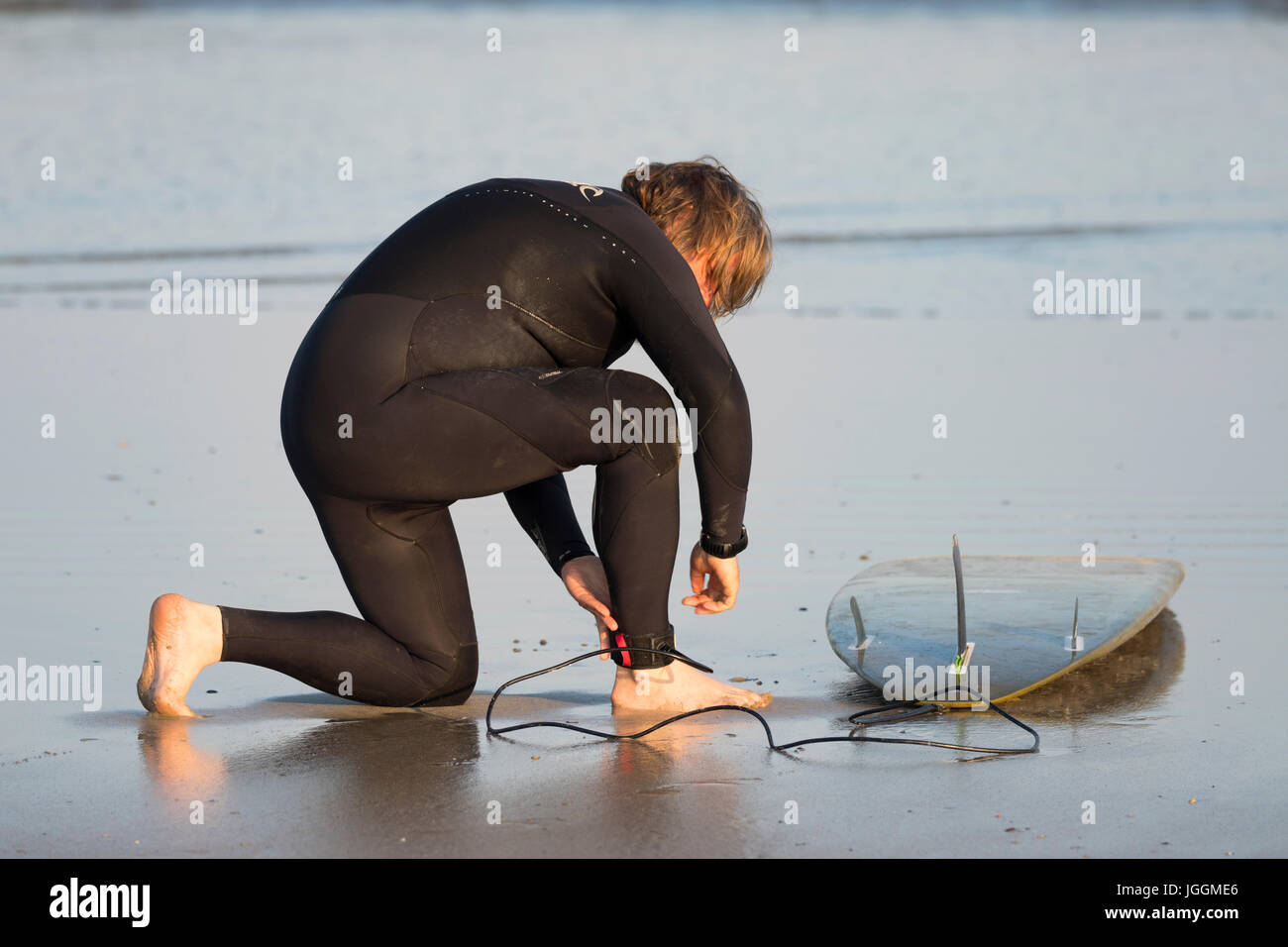 Ein reifer männlicher Surfer Befestigung ein Surfbrett Riemen an seinem Bein, bevor Sie sich ins Meer zu den beliebten Surf Strand Polzeath, Cornwall Stockfoto Ein reifer männlicher Surfer Befestigung ein Surfbrett Riemen an seinem Bein, bevor Sie sich ins Meer zu den beliebten Surf Strand Polzeath, Cornwall Stockfoto