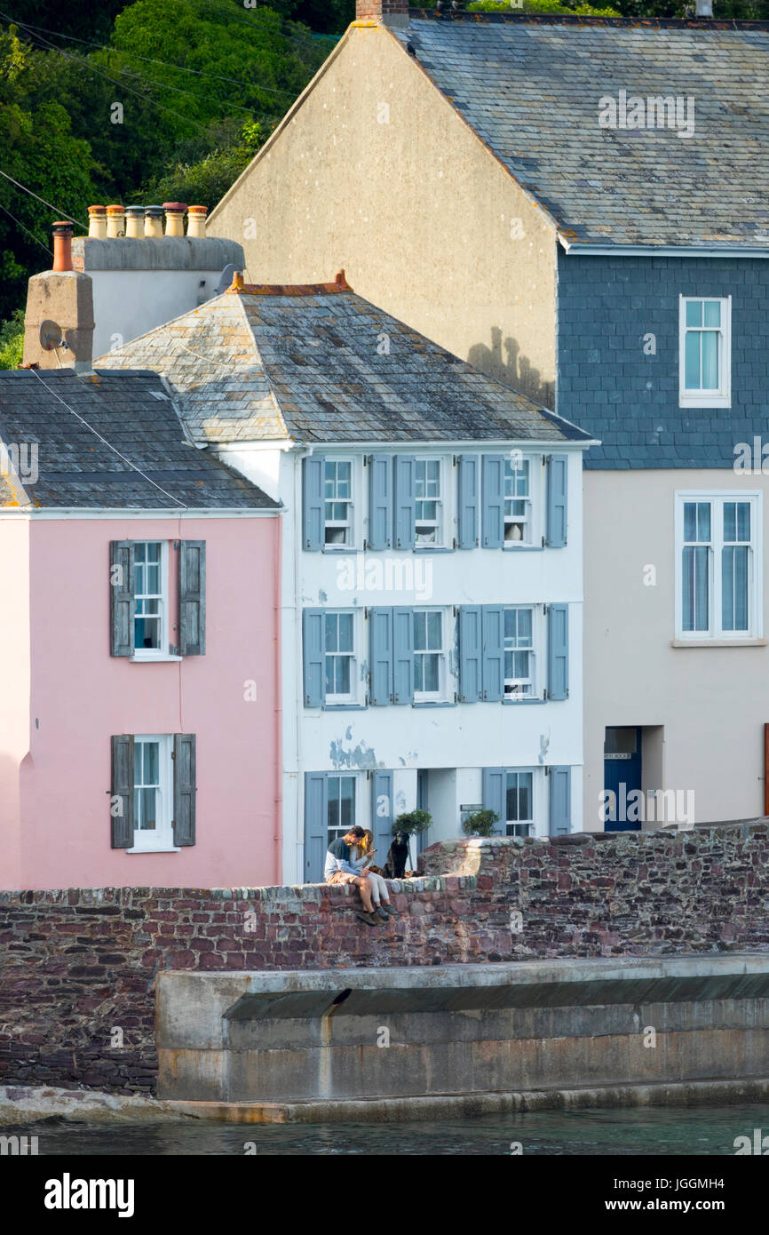 Menschen, die in einem Hafen an der malerischen englischen Küste Dorf Kingsand auf Rame Peninusla, Cornwall, England an einem Sommerabend entspannen Stockfoto