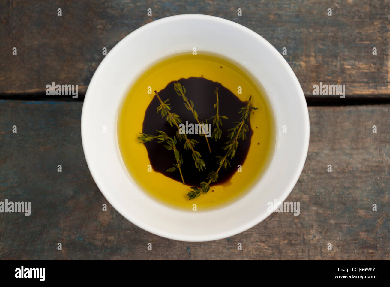 Draufsicht der Kräuter in Olivenöl auf Holztisch Stockfoto