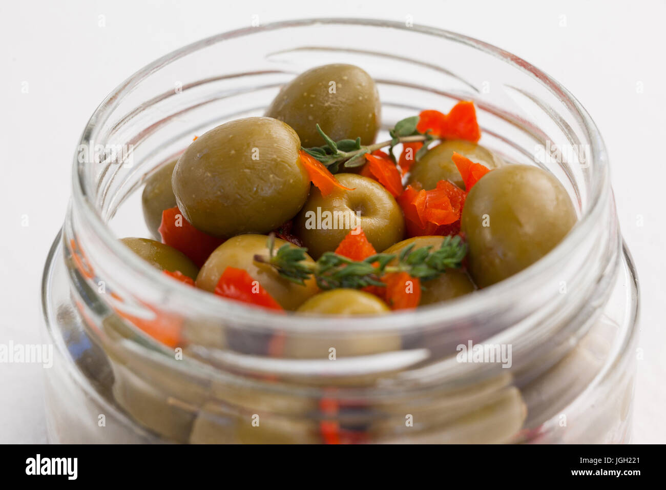 Grüne Oliven mit Kräutern in Glas am Tisch hautnah Stockfoto