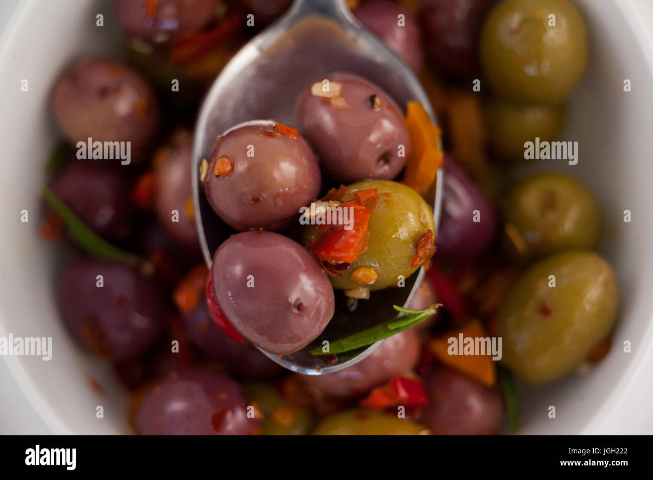 Nahaufnahme von Löffel mit Oliven mit Kräutern über container Stockfoto