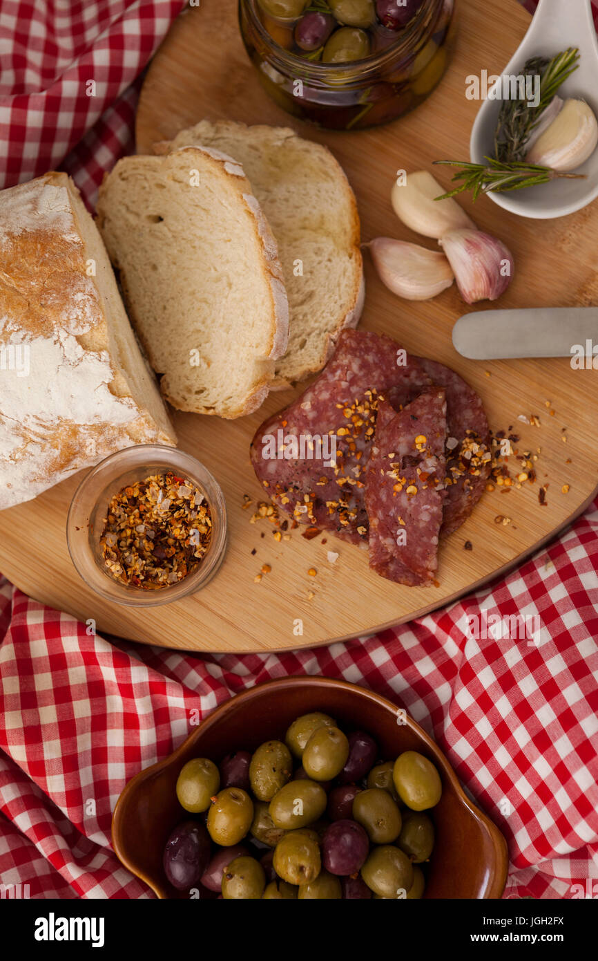 Draufsicht der Chili-Flocken auf Fleisch vom Brot mit Oliven im Glas am Tisch Stockfoto
