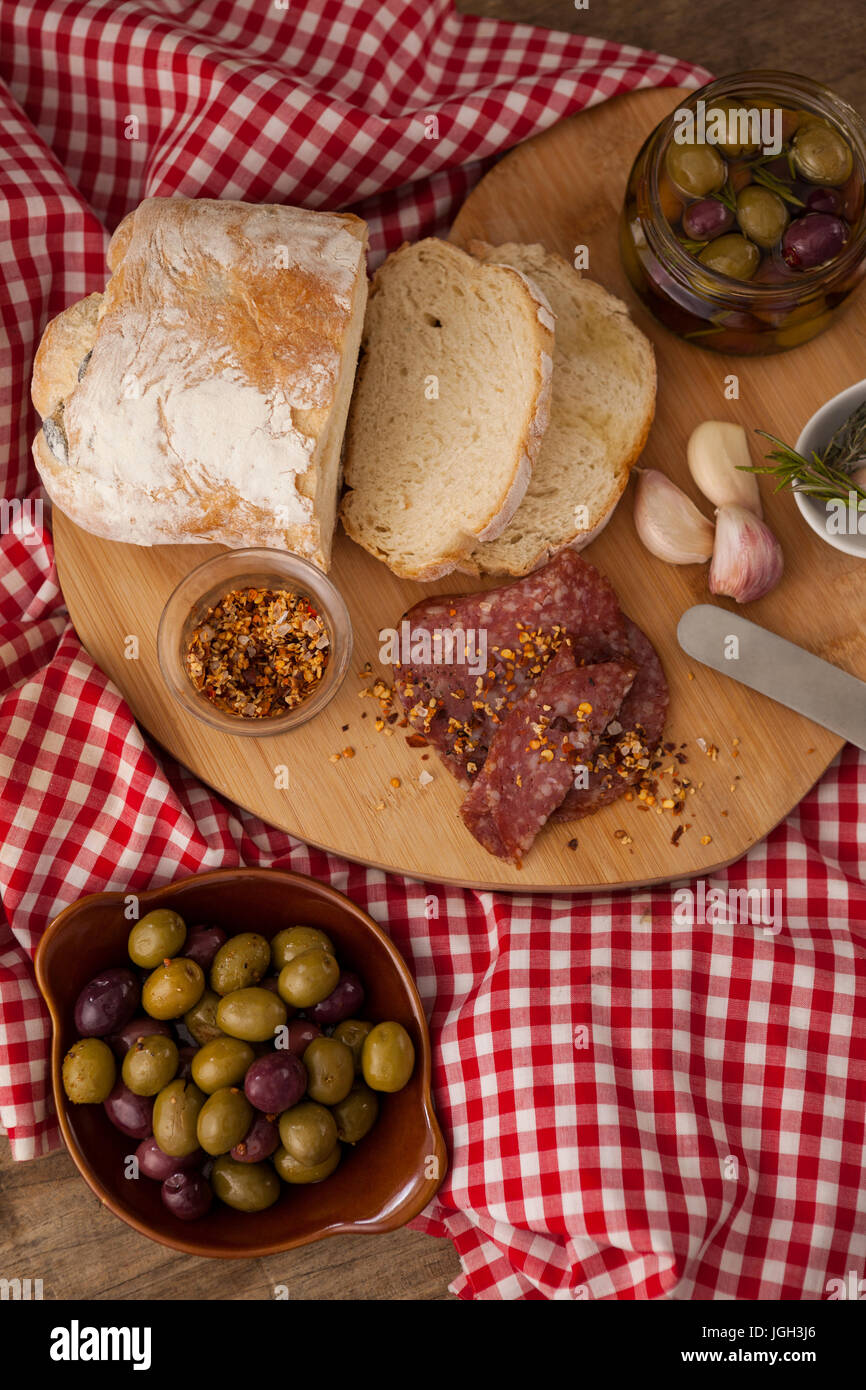 Direkt über die Aufnahme von Brot und Oliven mit Fleisch auf Serviette auf Holztisch Stockfoto