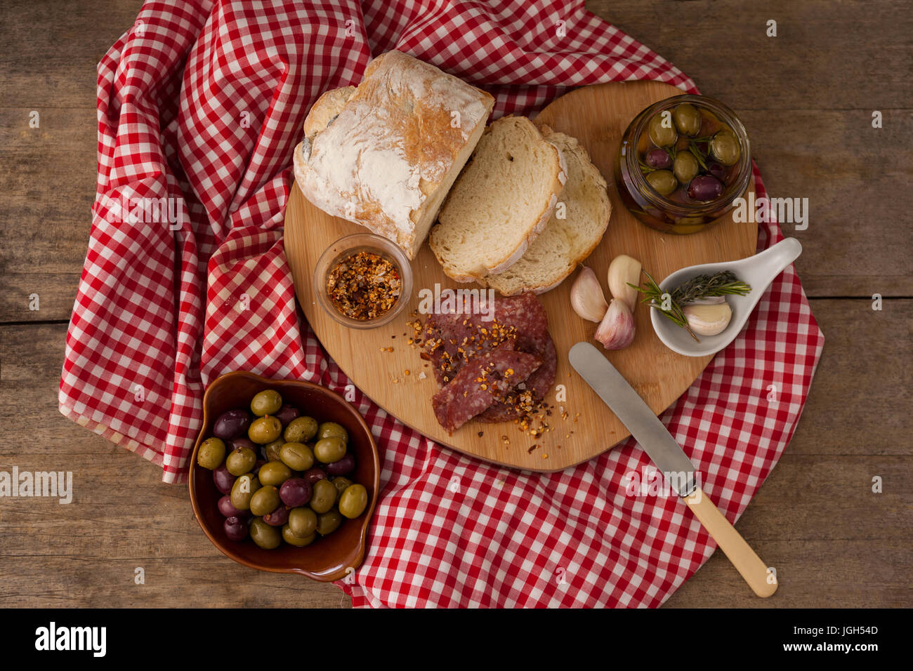 Draufsicht von Brot und Oliven mit Fleisch auf Serviette auf Holztisch Stockfoto