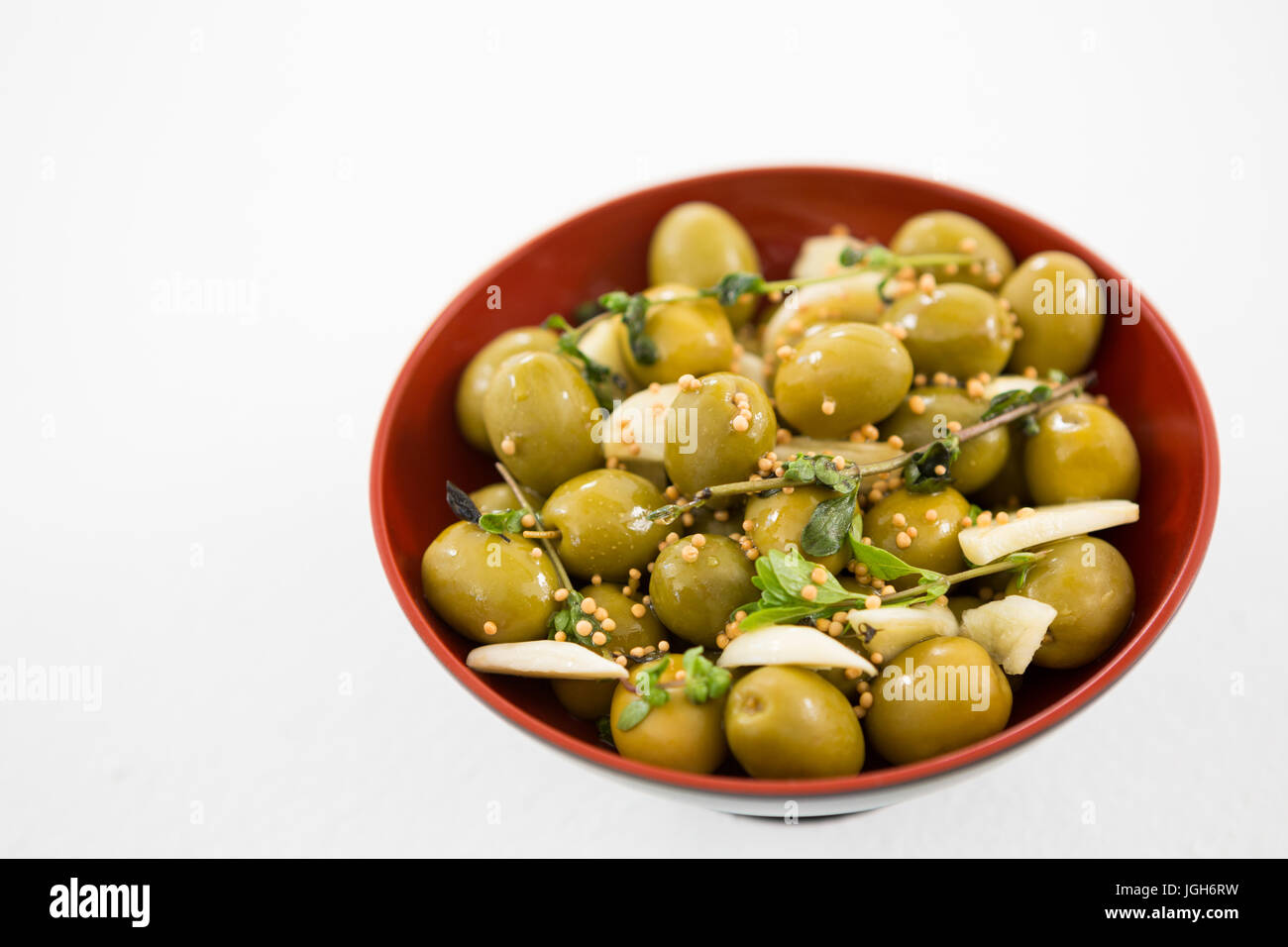 Marinierte Oliven mit Knoblauch und Kräutern in Schüssel in Nahaufnahme Stockfoto