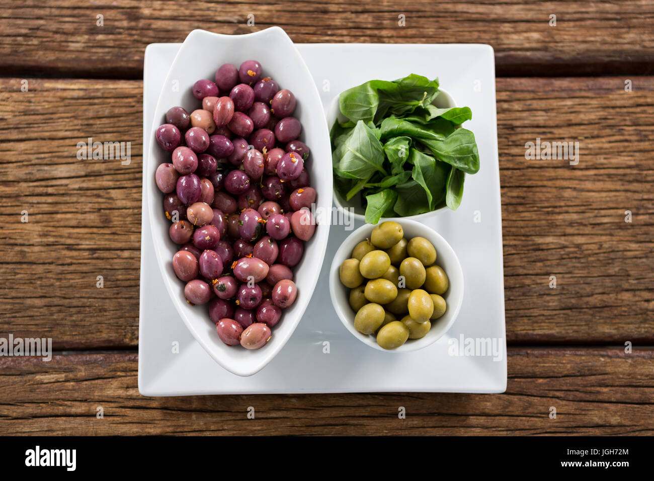 Marinierte Oliven mit Kräutern in Schüssel auf Holztisch Stockfoto