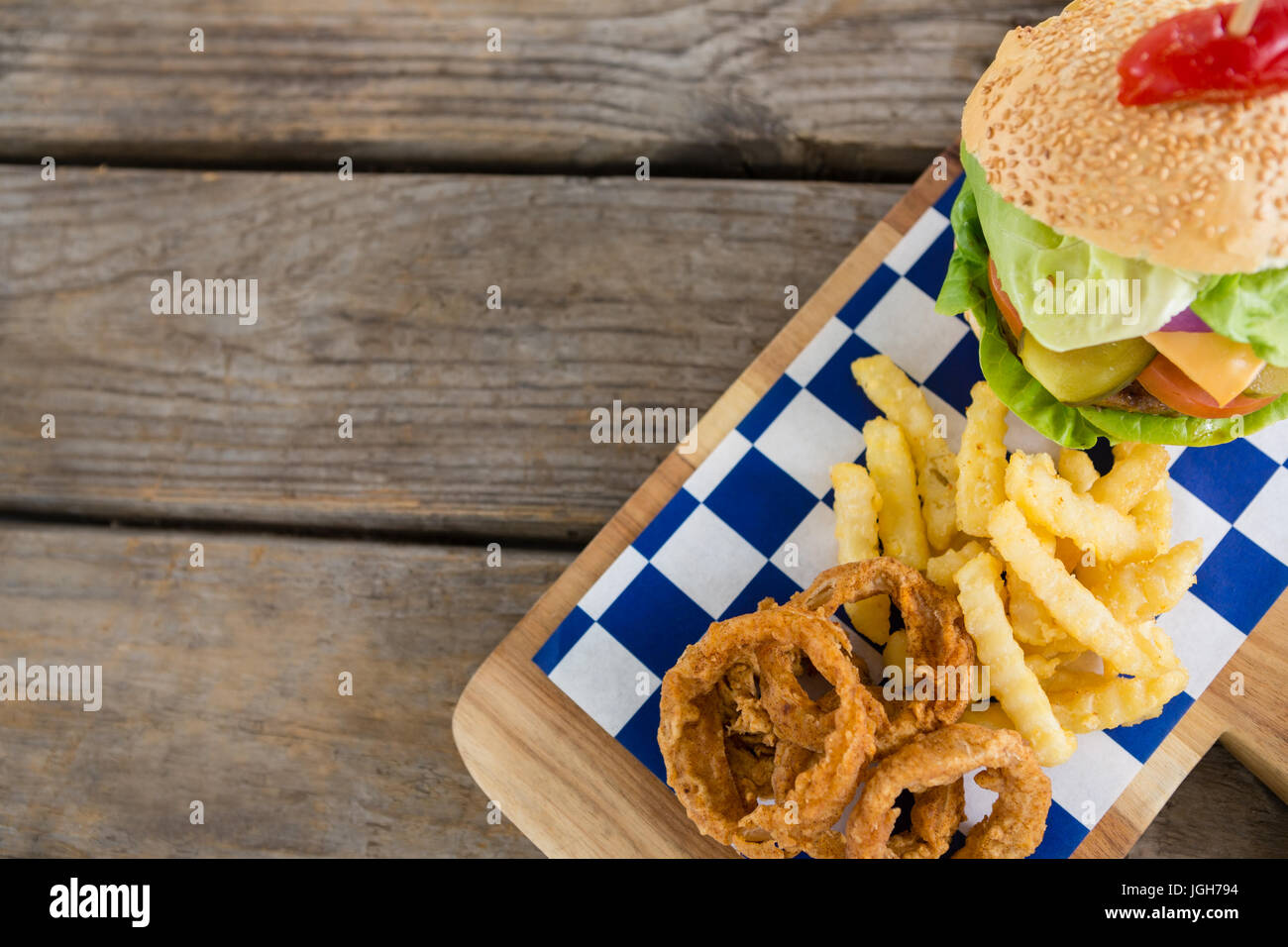 Draufsicht der gebratenen Zwiebel Ringe mit Pommes Frites von Burger auf Schneidebrett am Tisch Stockfoto