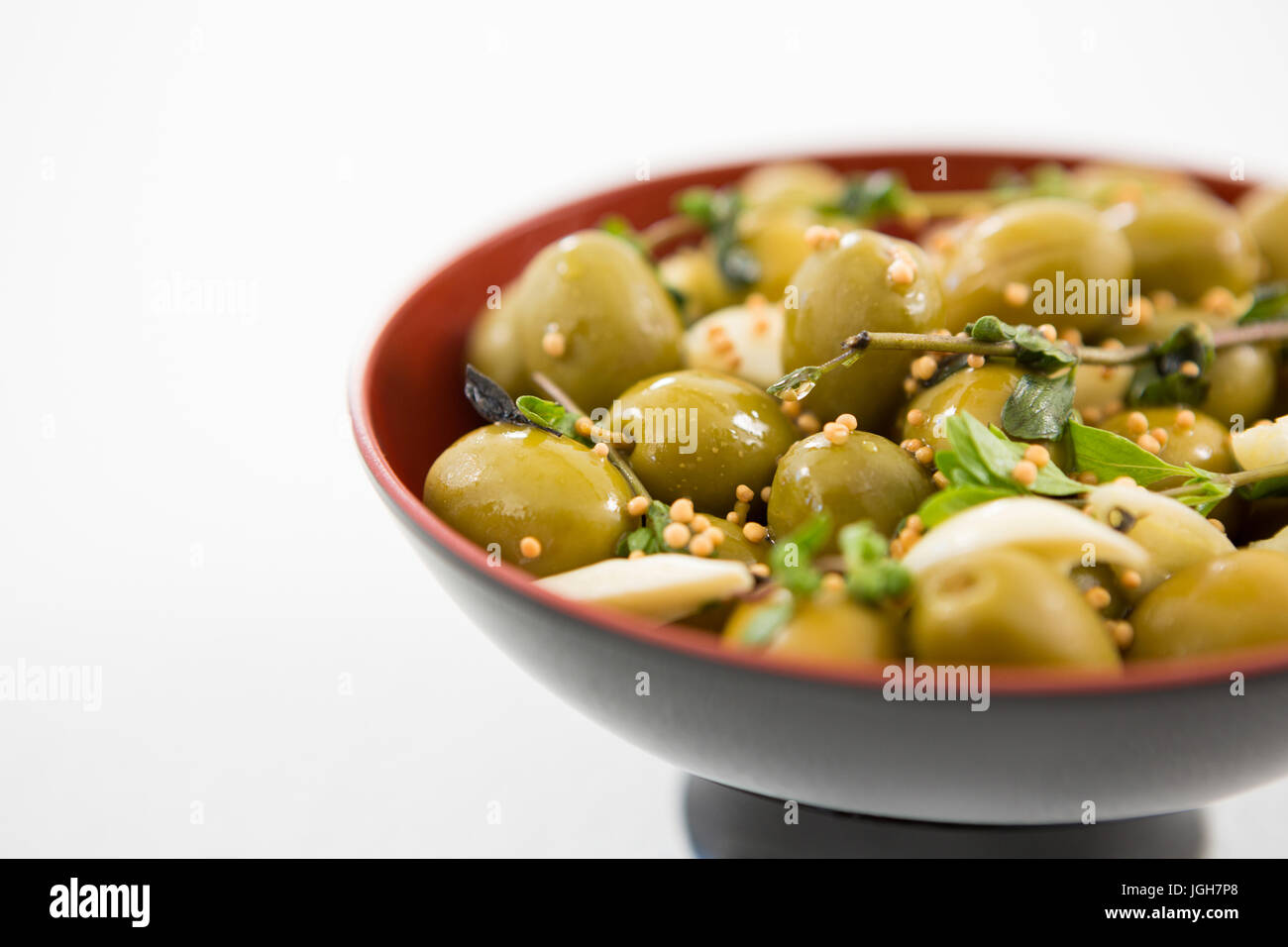 Marinierte Oliven mit Knoblauch und Kräutern in Schüssel in Nahaufnahme Stockfoto