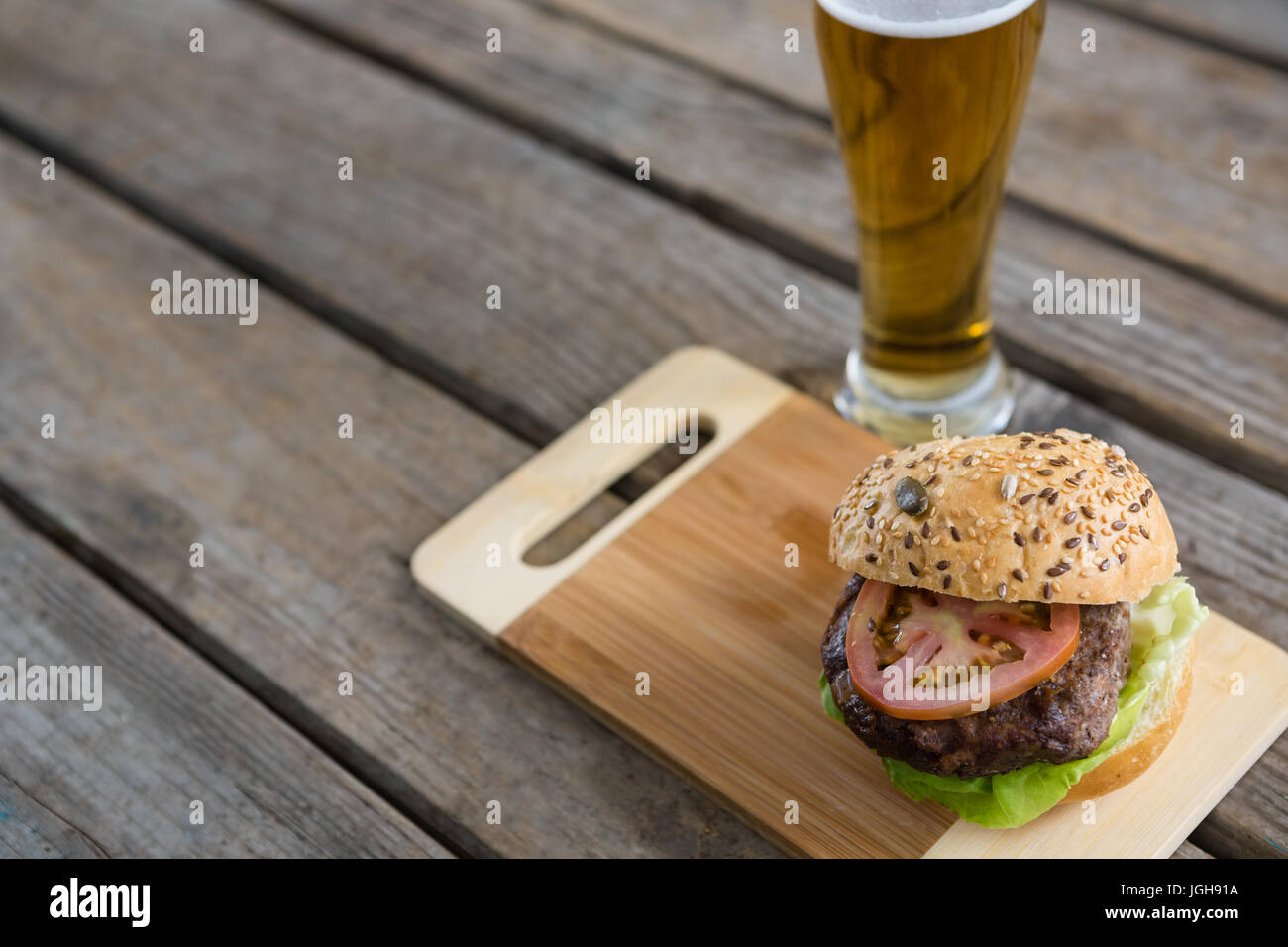 Erhöhte Ansicht der Hamburger auf Schneidebrett Glas Bier am Tisch Stockfoto