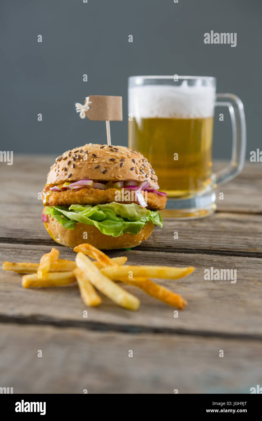Pommes Frites mit Burger und Bier Glas auf Tisch Wand hautnah Stockfoto