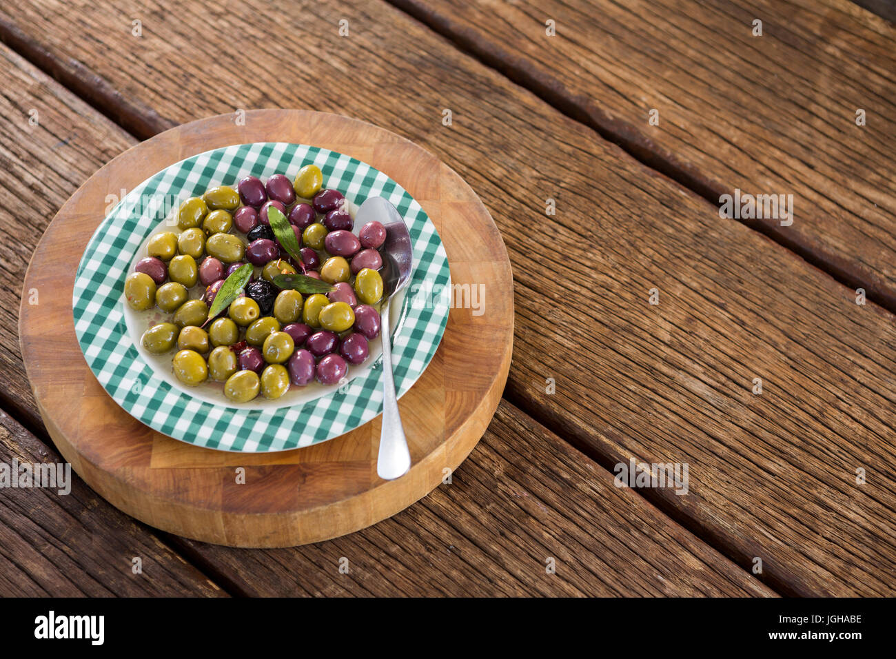 Marinierte Oliven mit Kräutern auf Holzbrett in Nahaufnahme Stockfoto