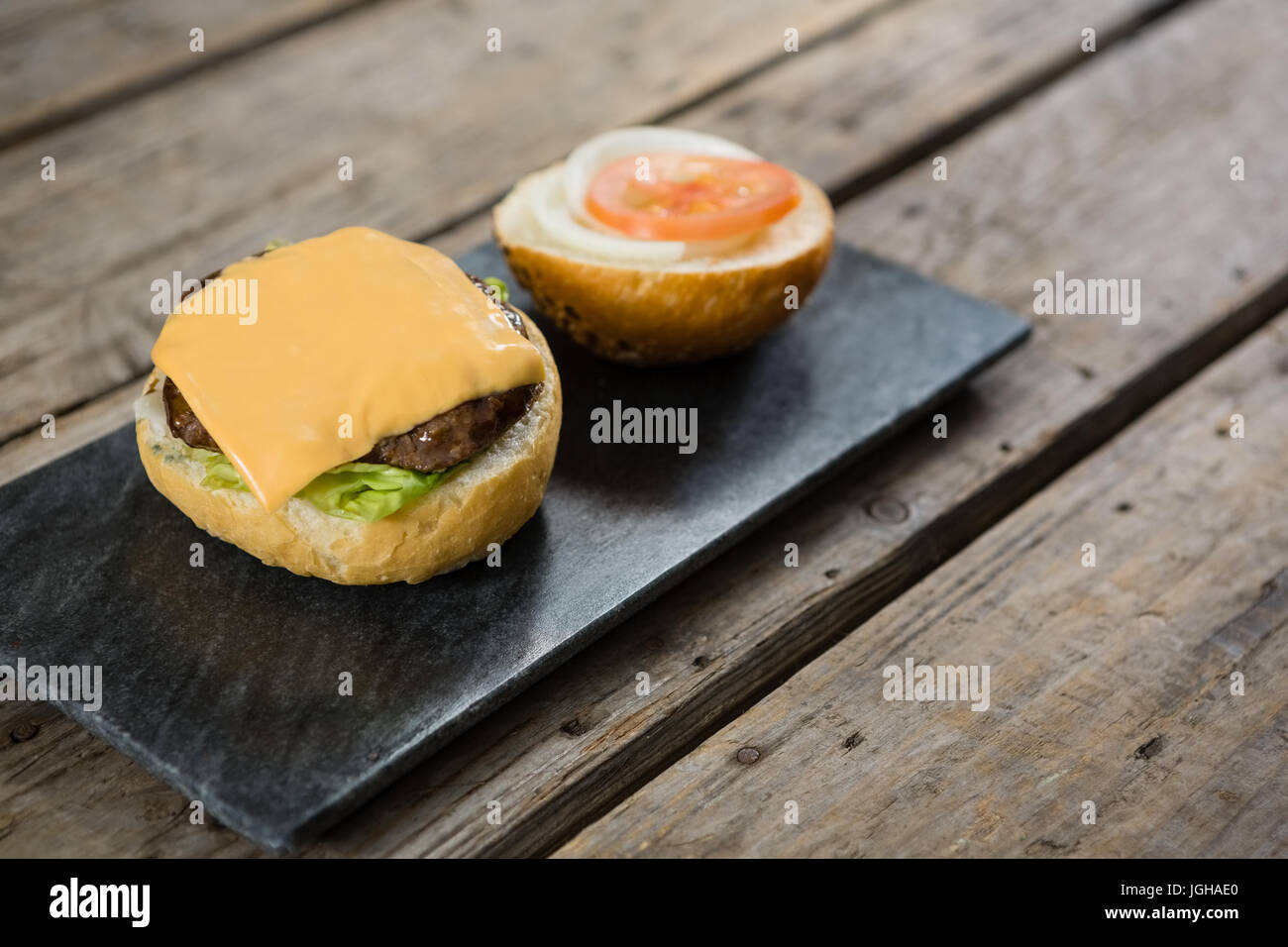 Käse und Fleisch mit Brötchen auf Schiefer am Holztisch Stockfoto