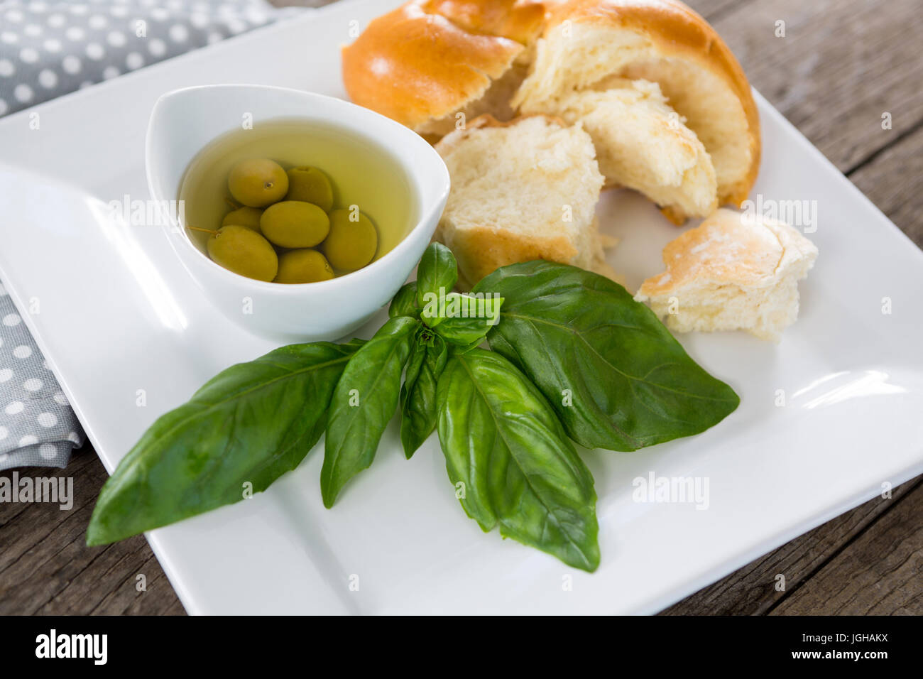 Eingelegte Oliven mit Kräutern und Brot in Plattenteller auf Holztisch Stockfoto