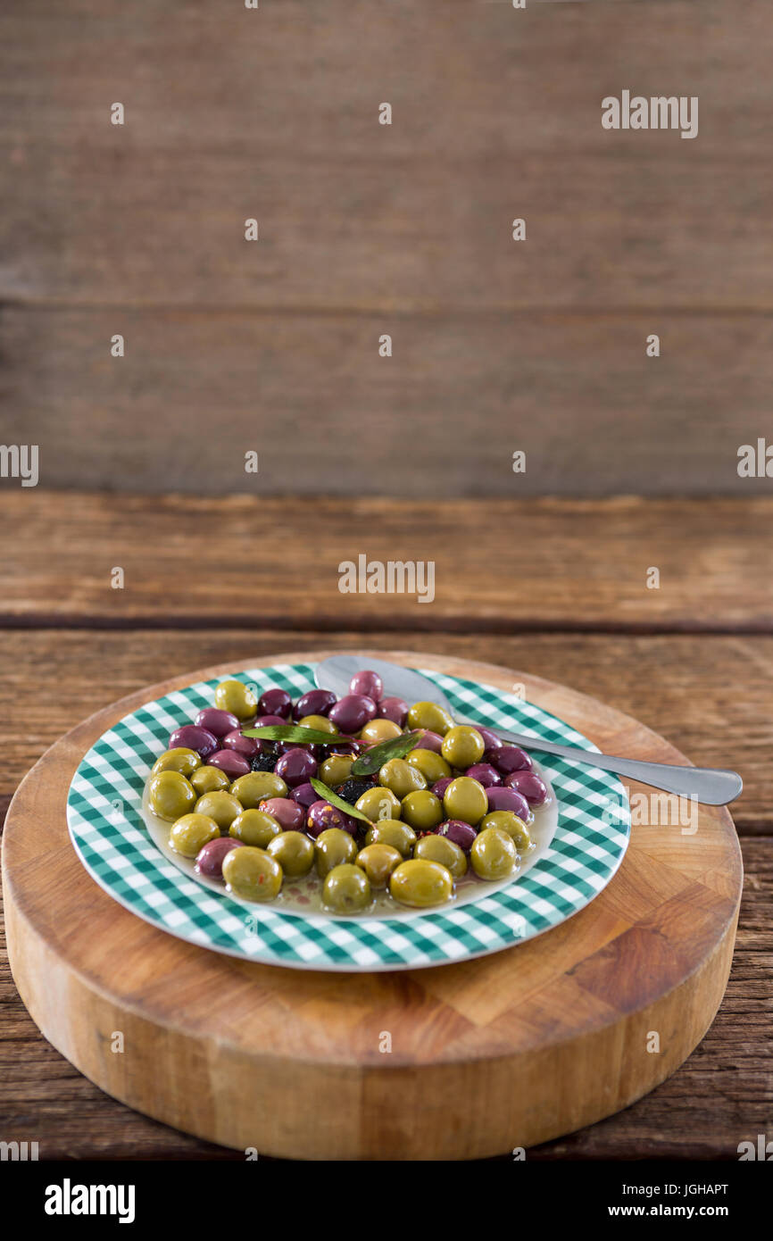 Marinierte Oliven mit Kräutern auf Holzbrett in Nahaufnahme Stockfoto