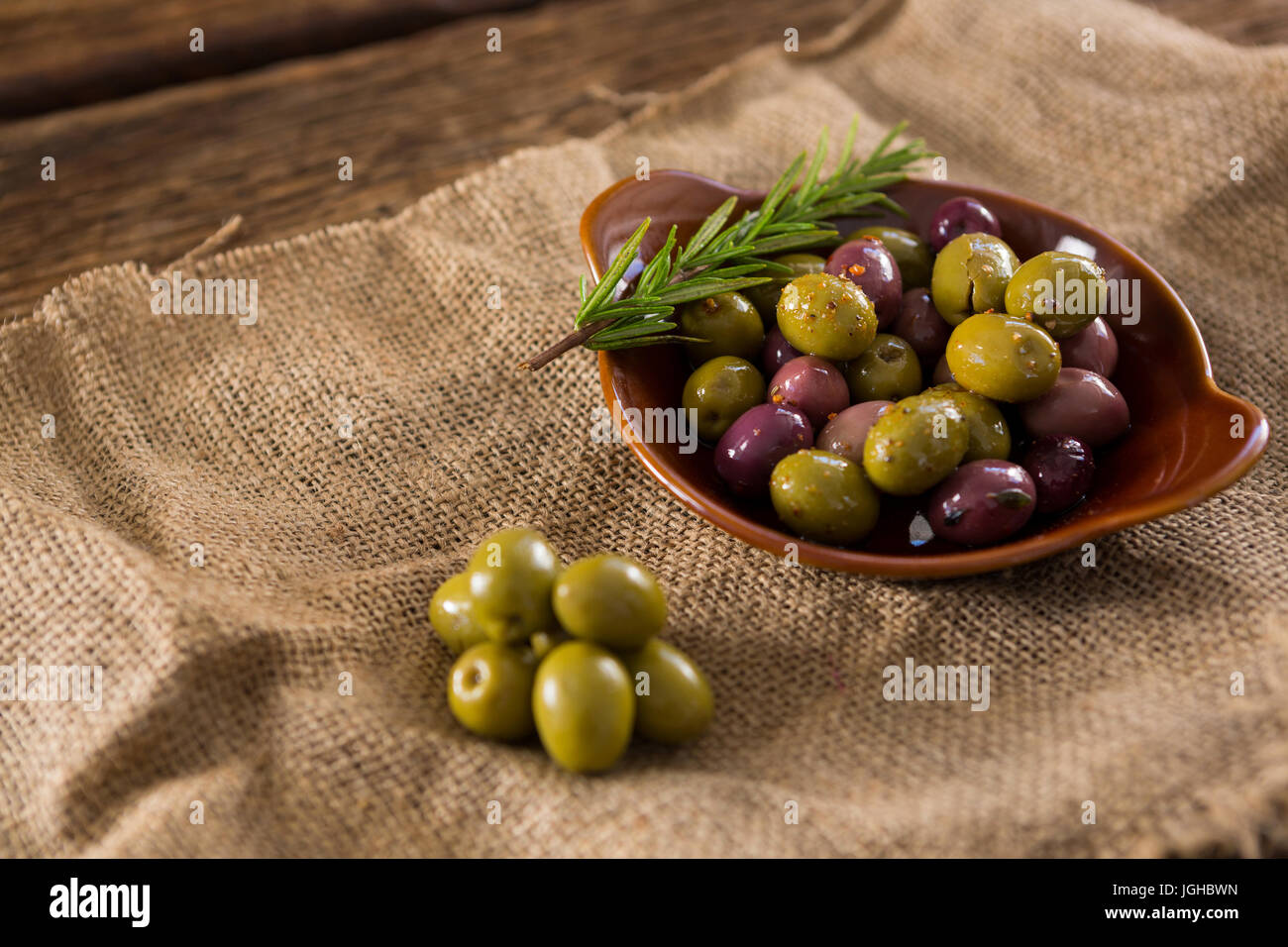 Marinierte Oliven mit Kräutern auf Sackleinen in Nahaufnahme Stockfoto
