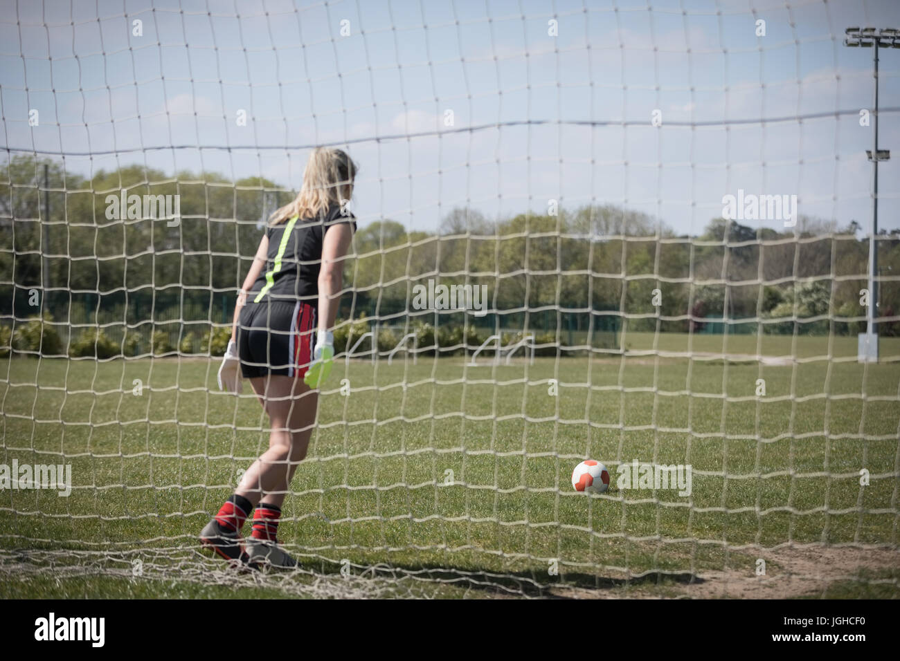 Rückseite Blick voller Länge der Frau spielen Fußball auf Feld Stockfoto