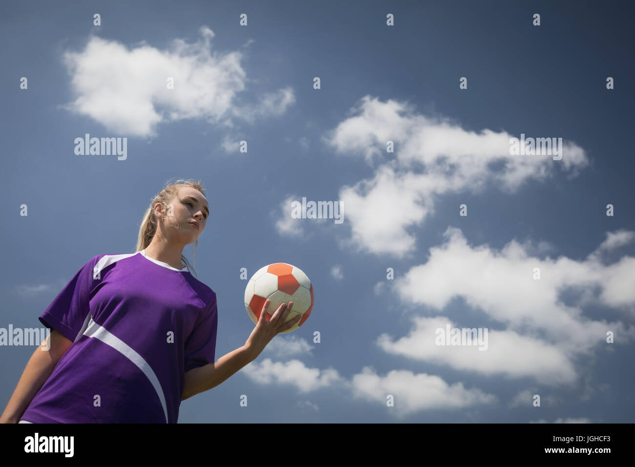 Niedrigen Winkel Blick der jungen Frau, die mit Fußball gegen Himmel Stockfoto