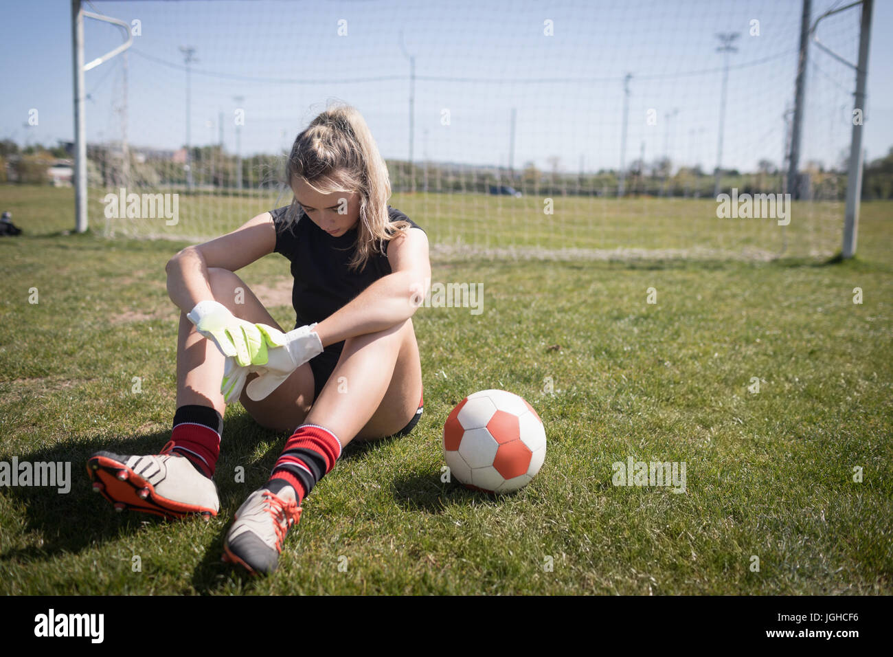 Voller Länge des weiblichen Fußballer ruht auf Spielfeld an sonnigen Tag Stockfoto