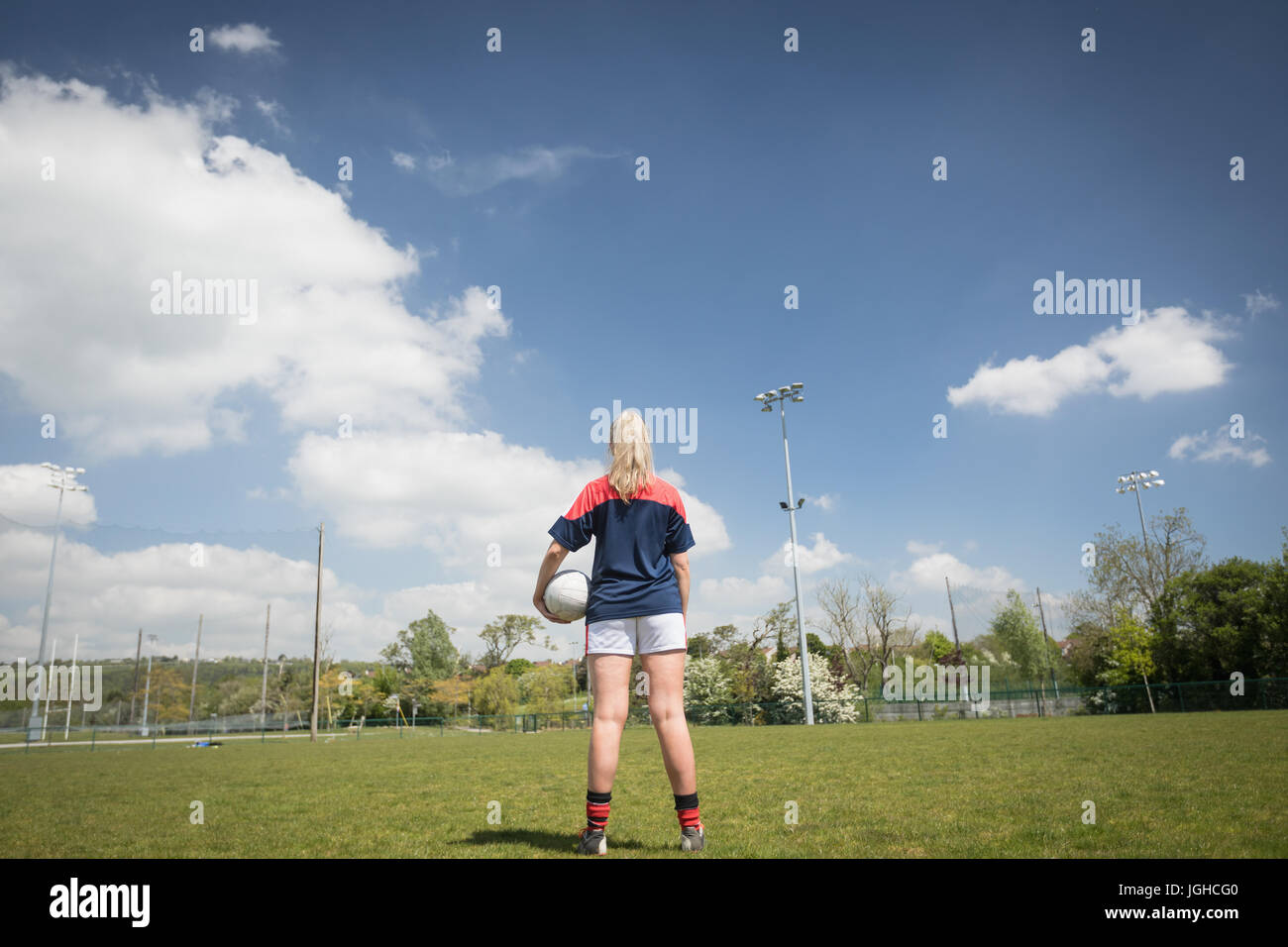 Rückansicht des weiblichen Fußballspieler mit Ball auf Feld gegen Himmel Stockfoto
