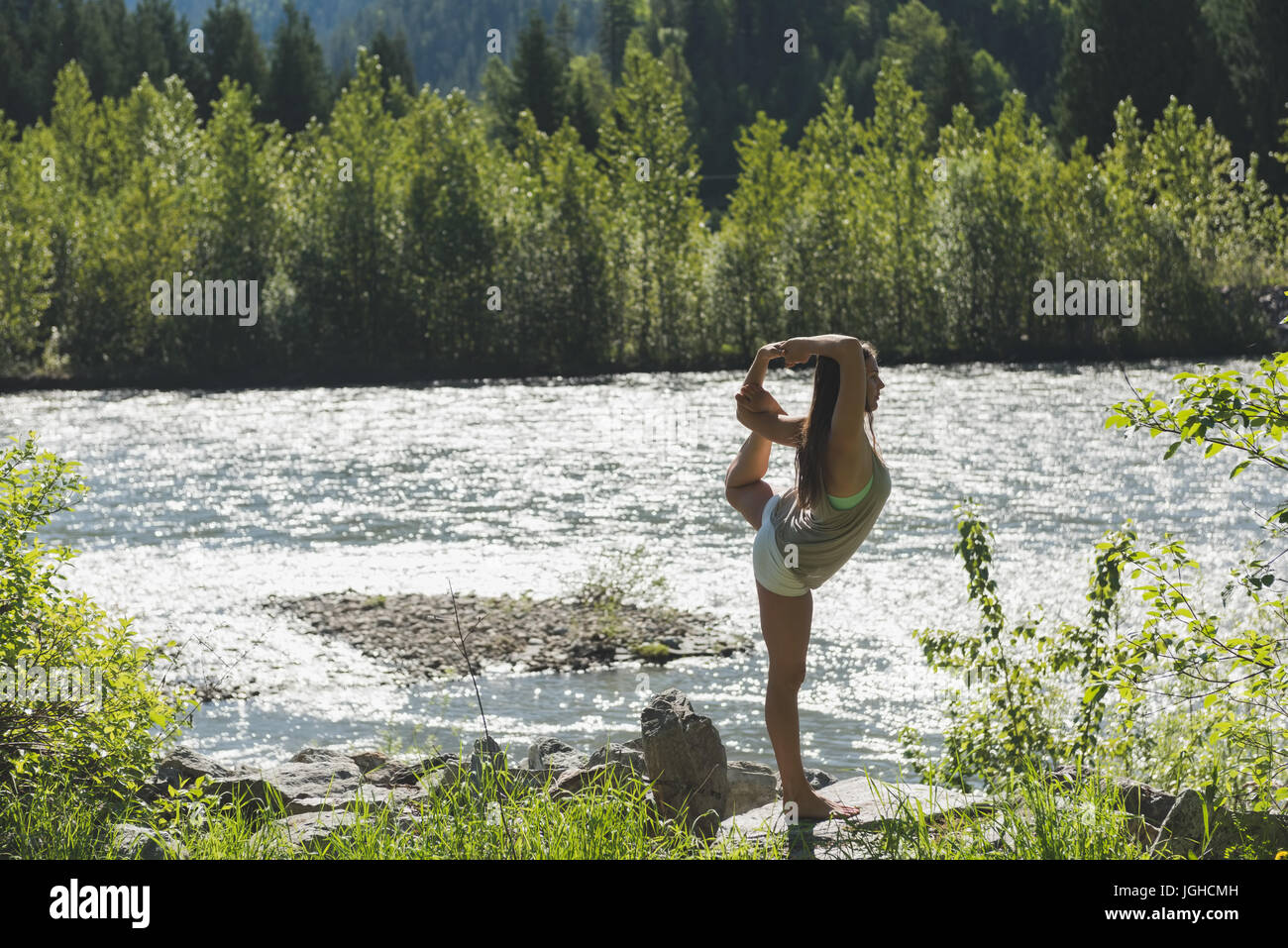 Frau, die Yoga in der Nähe von Riverside an einem sonnigen Tag machen Stockfoto