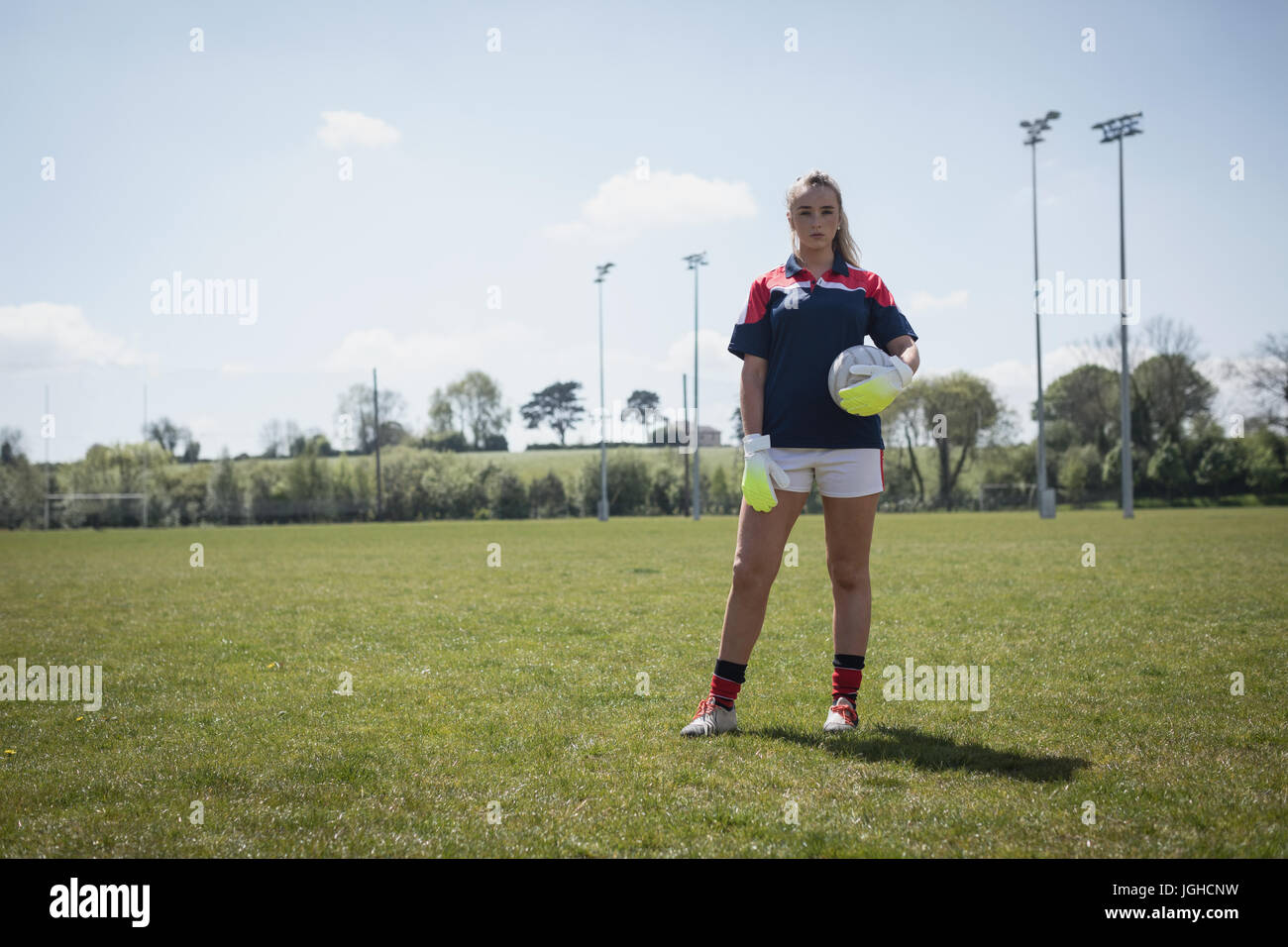 Volle Länge des weiblichen Torwart stehend mit Fußball auf Feld gegen Himmel Stockfoto