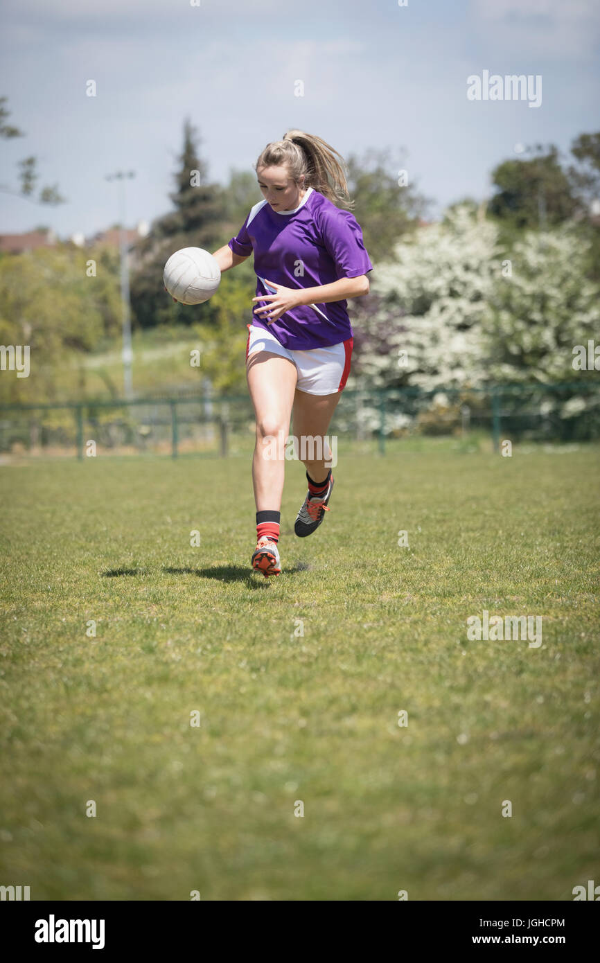 Gesamte Länge der Frau läuft mit Fußball auf Feld an sonnigen Tag Stockfoto