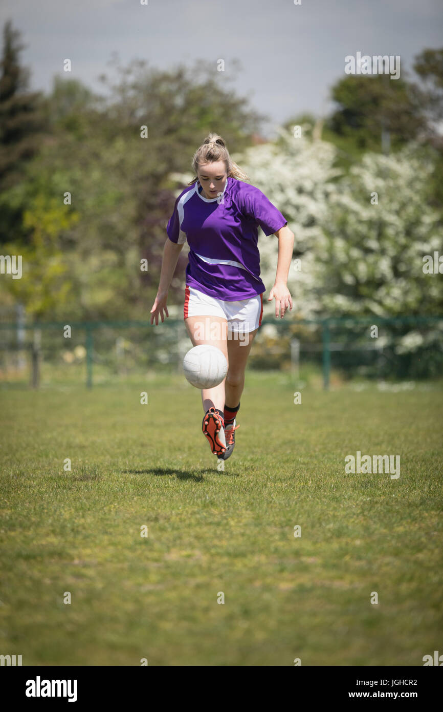 Voller Länge jungen Frau spielen Fußball auf Feld an sonnigen Tag Stockfoto