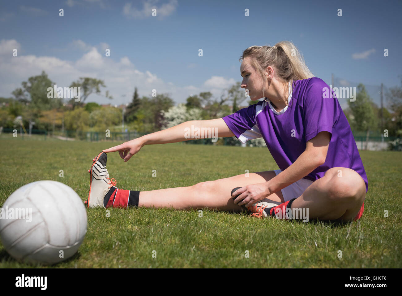 Voller Länge des weiblichen Fußballer von Ball stretching auf Feld Stockfoto